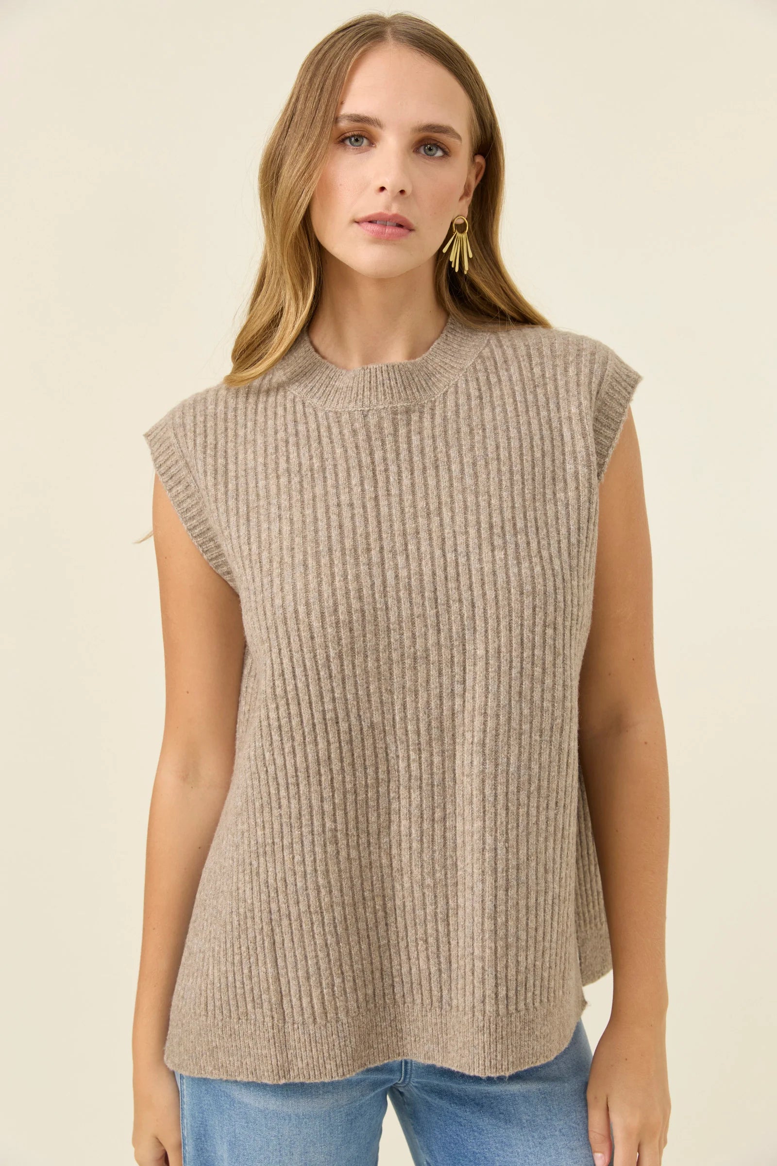 Woman wearing a Isle of Mine beige sleeveless knitted top against a plain background