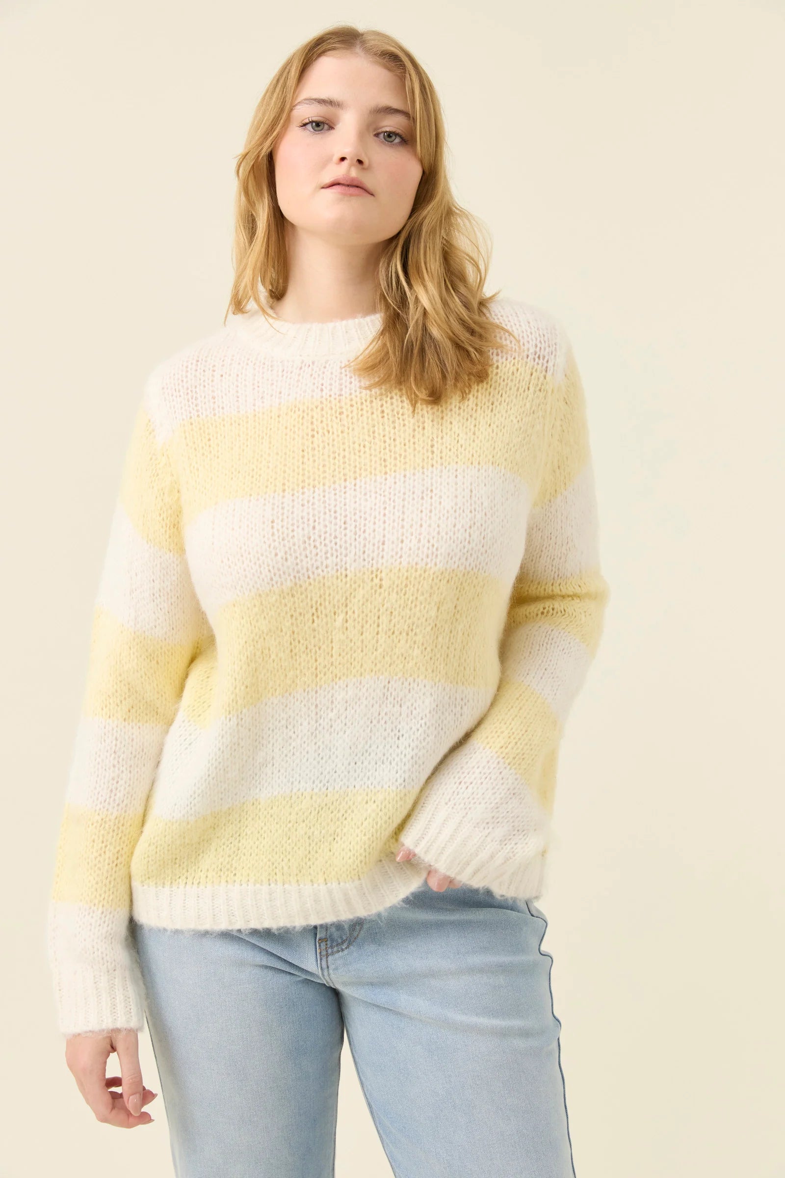 Image of Woman wearing a Isle of Mine yellow and white striped sweater against a plain background