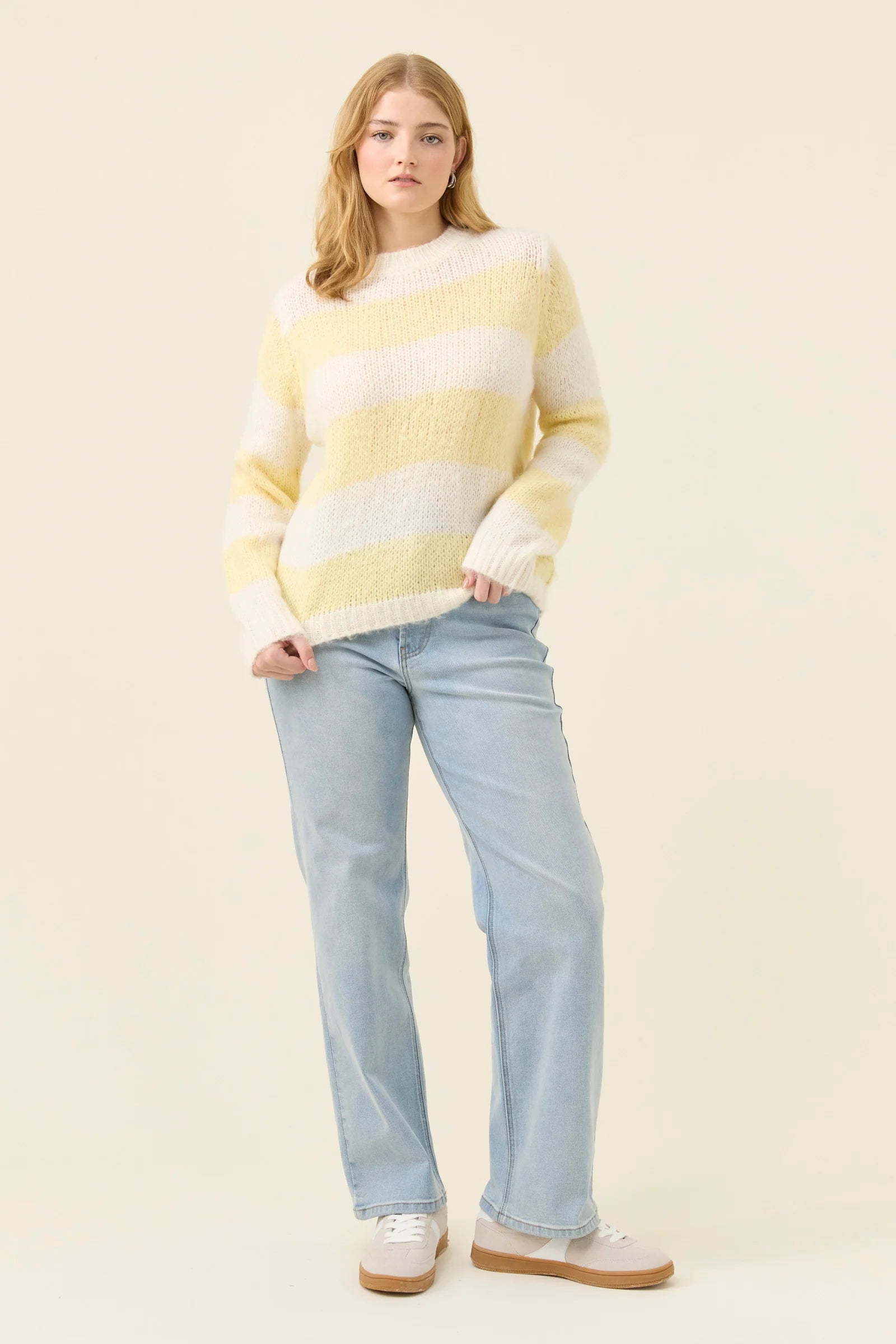 Image of Woman wearing a Isle of Mine yellow and white striped sweater against a plain background