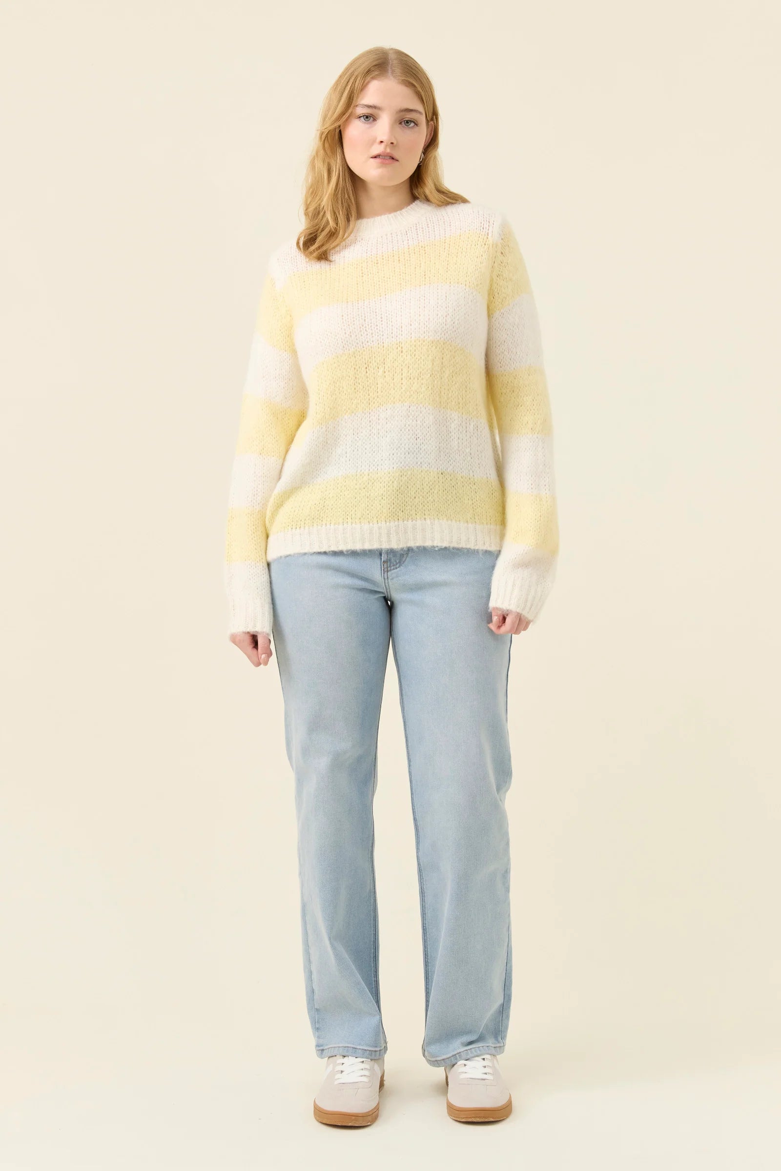 Image of Woman wearing a Isle of Mine yellow and white striped sweater against a plain background