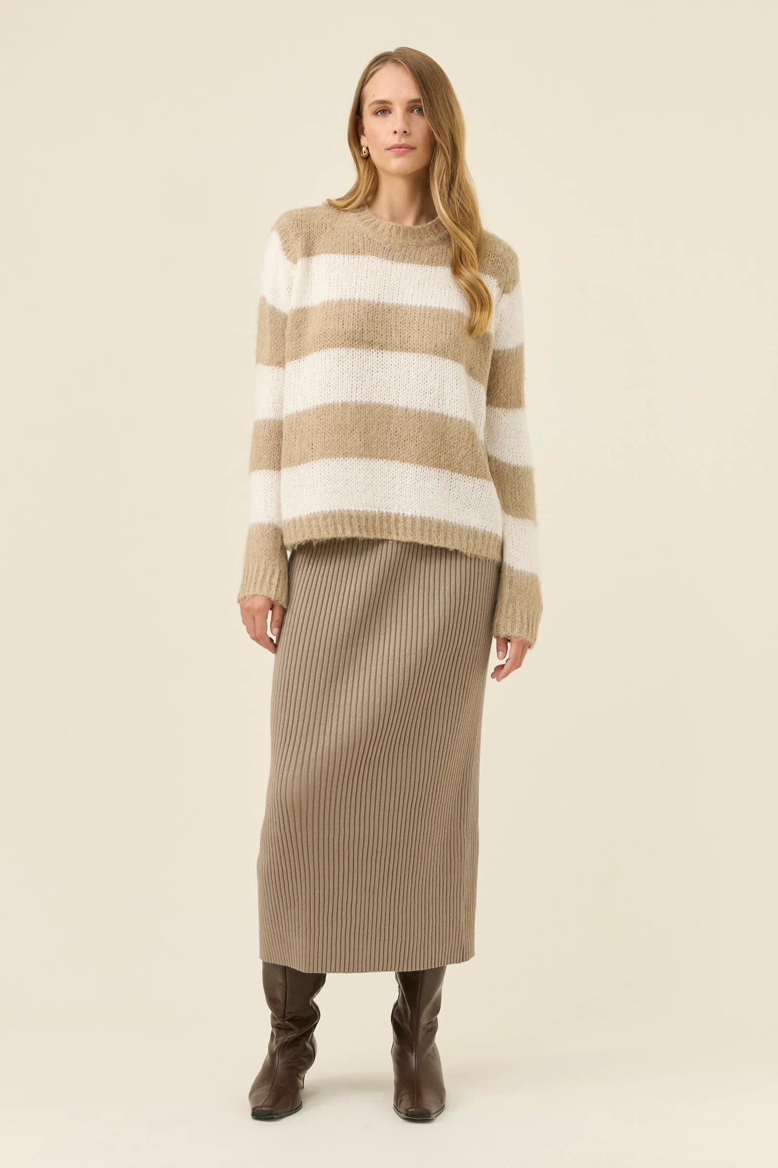 Woman wearing Isle of Mine stripe knit jumper paired with Isle of Mine knit skirt with boots on a plain background