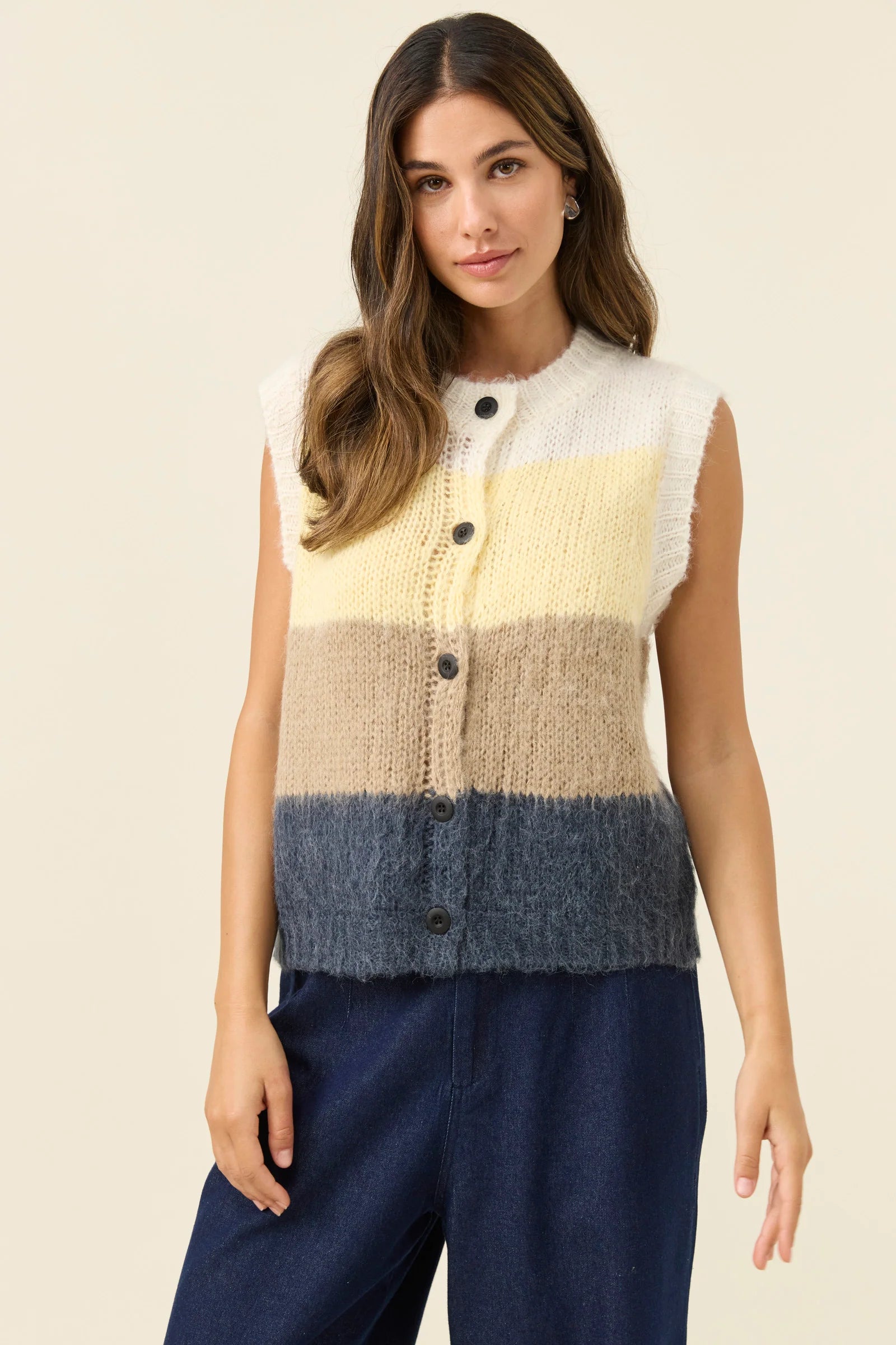 Woman wearing Isle of Mine Pallas Stripe Knit Vest in butter paired with denim jeans on a plain background 