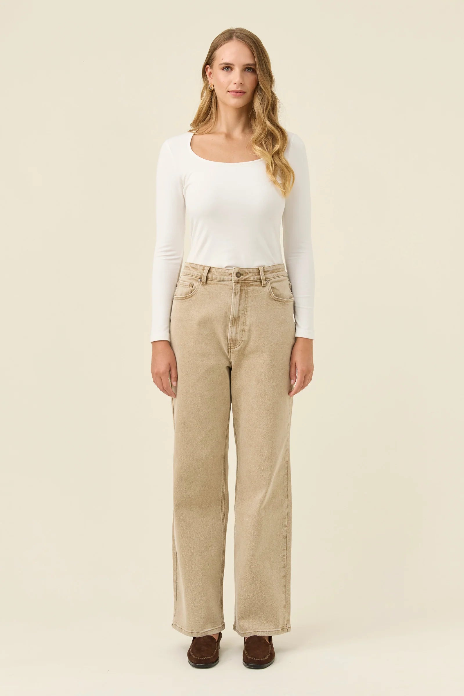 Woman wearing Isle of Mine jeans paired with a white long sleeve on a plain background