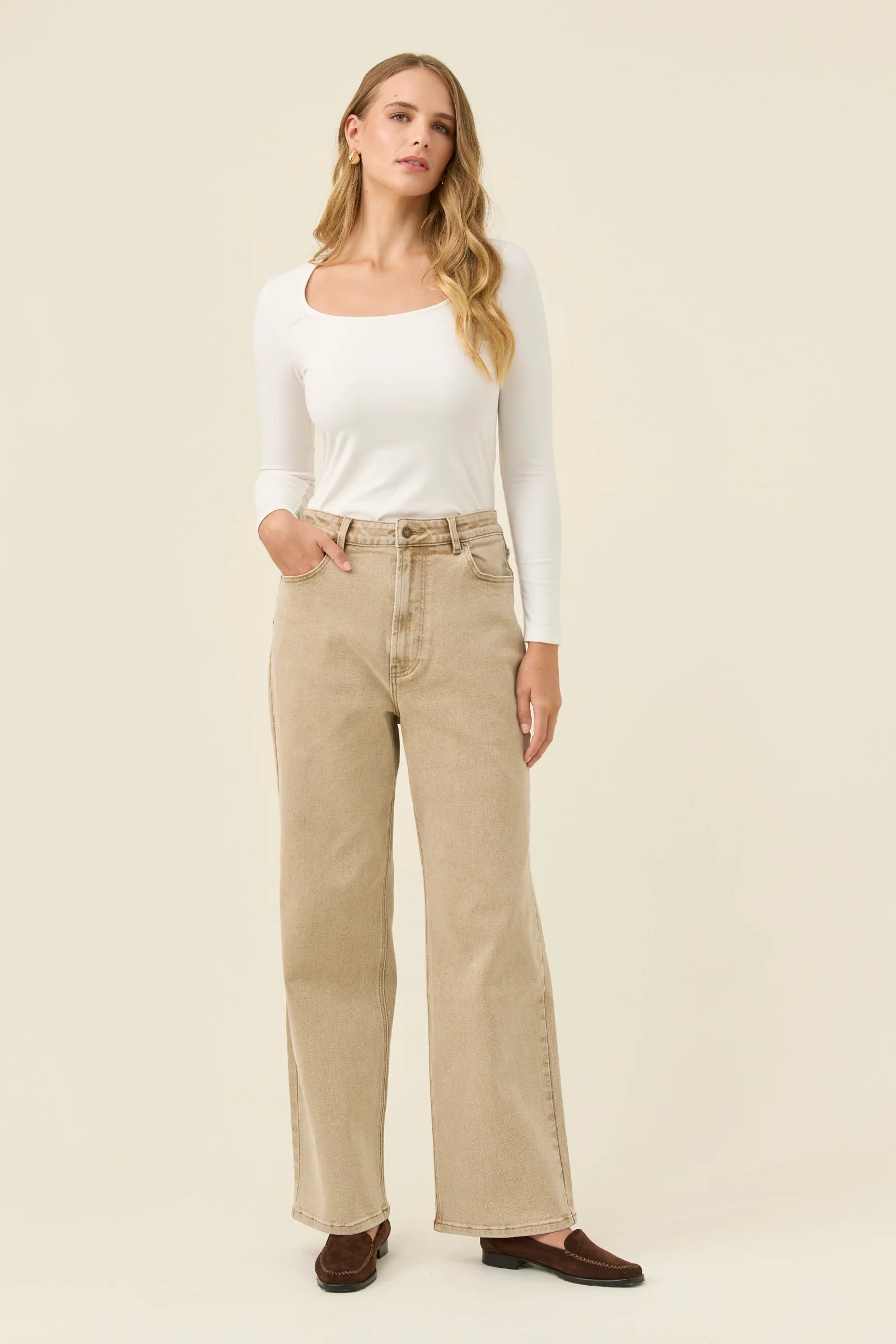 Woman wearing Isle of Mine jeans paired with a white long sleeve on a plain background