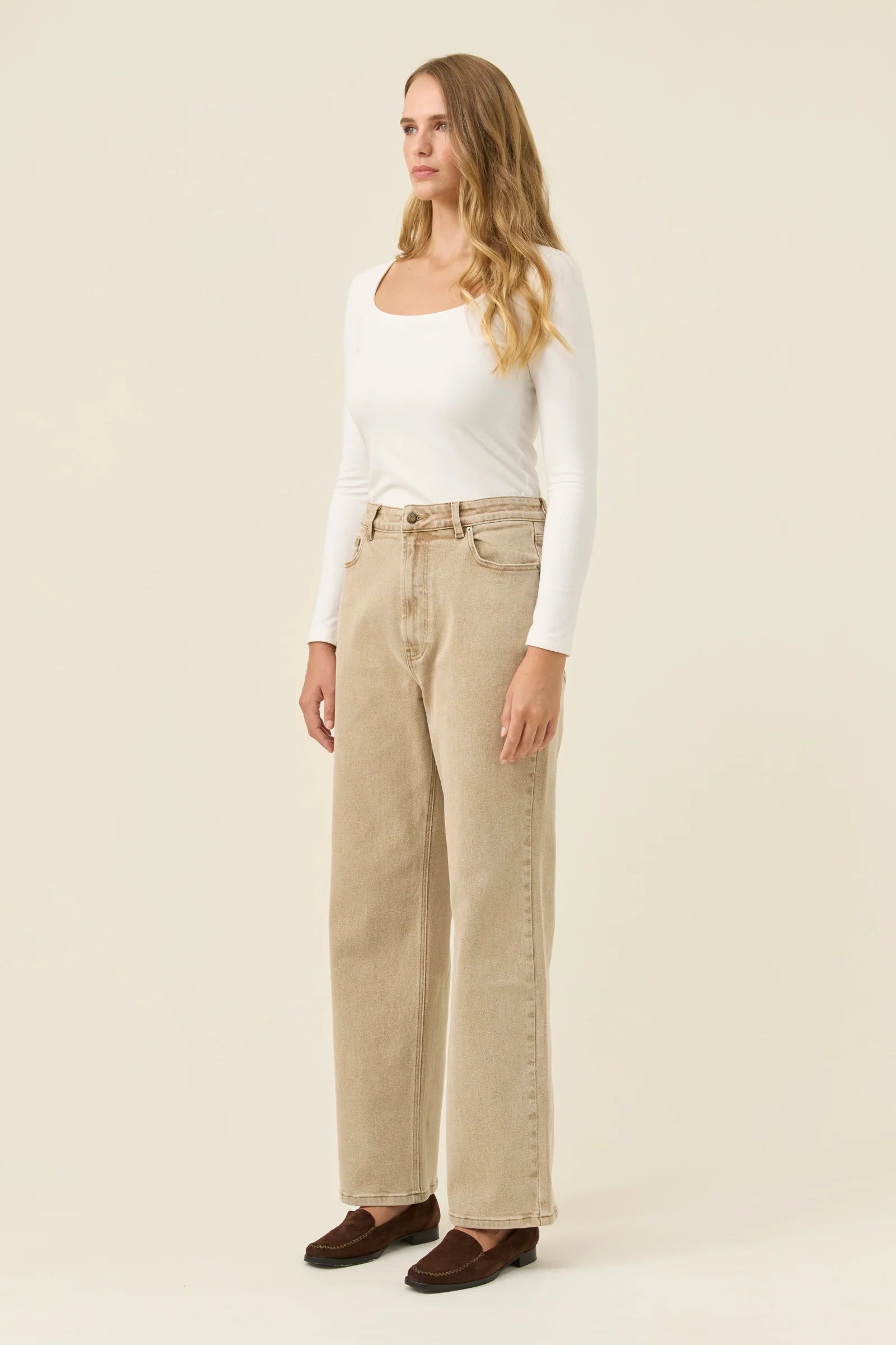 Woman wearing Isle of Mine jeans paired with a white long sleeve on a plain background