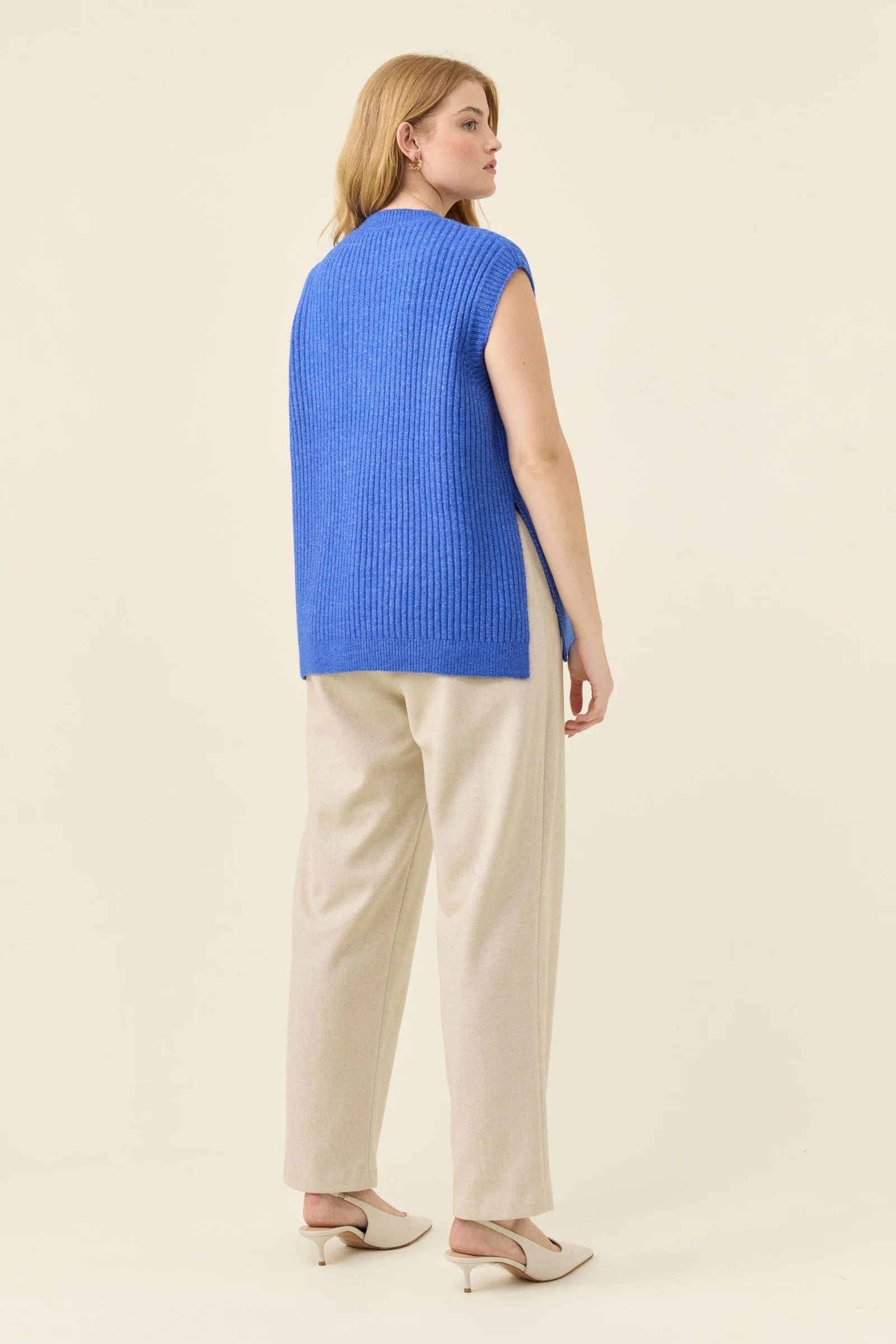 Image of Woman wearing a Isle of Mine blue sleeveless top and beige pants on a light background