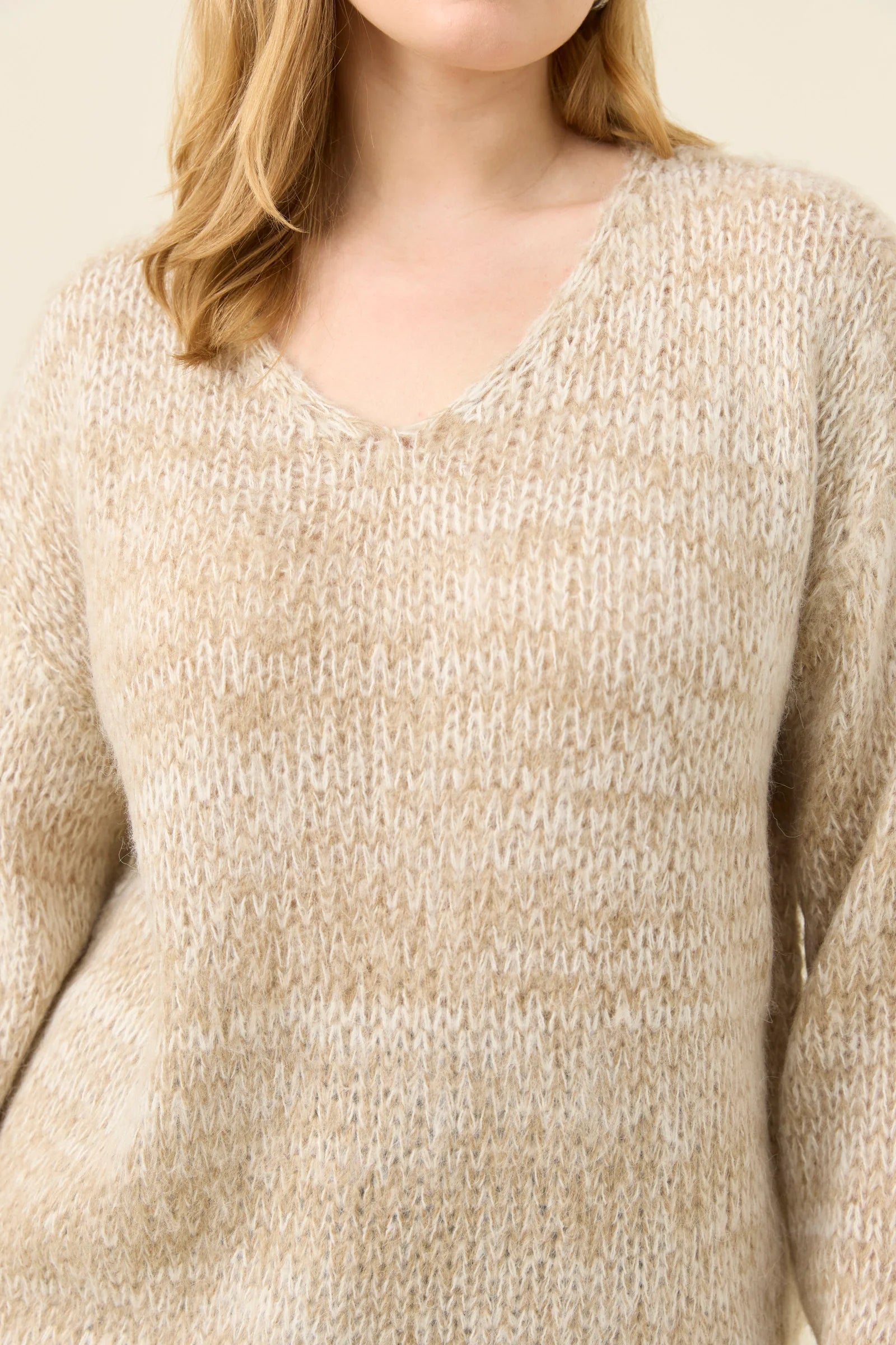 Woman wearing Isle of Mine knit in stone coloured. Paired with denim jeans on a plain background 