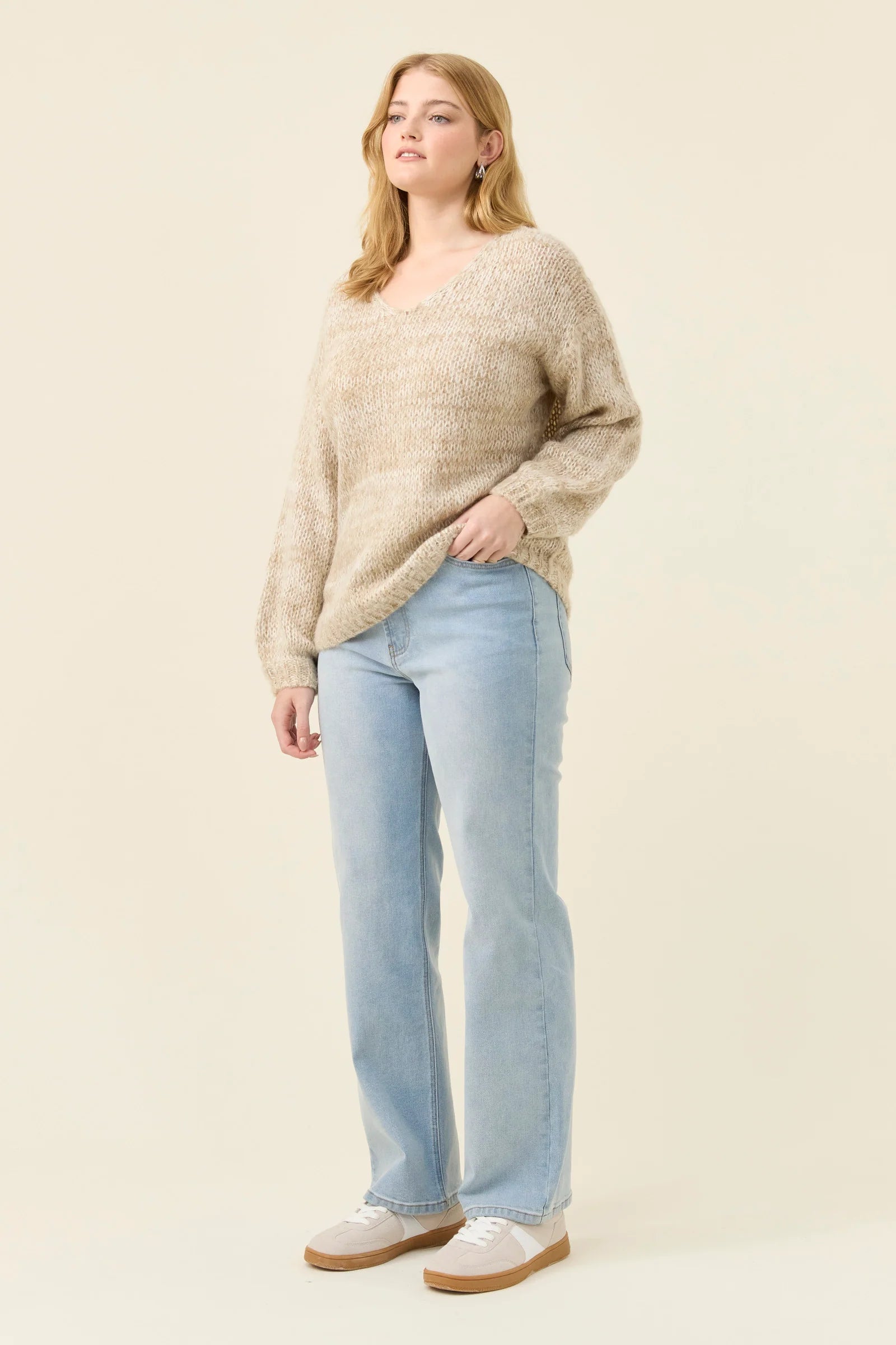 Image of Woman wearing Isle of Mine knit in stone coloured. Paired with denim jeans on a plain background 