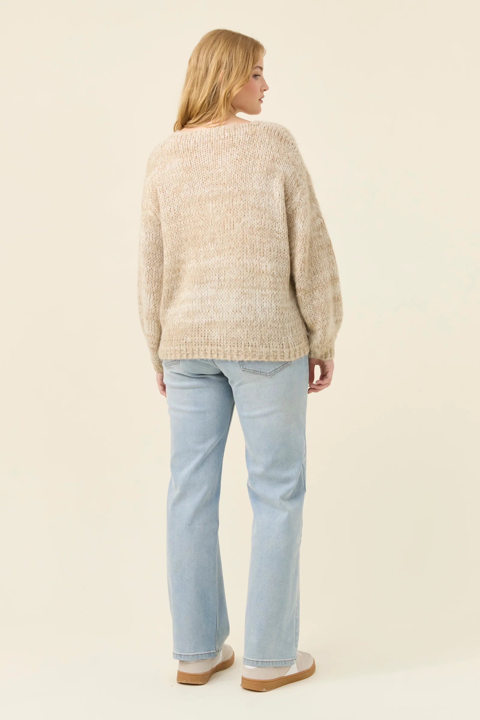 Woman wearing Isle of Mine knit in stone coloured. Paired with denim jeans on a plain background 