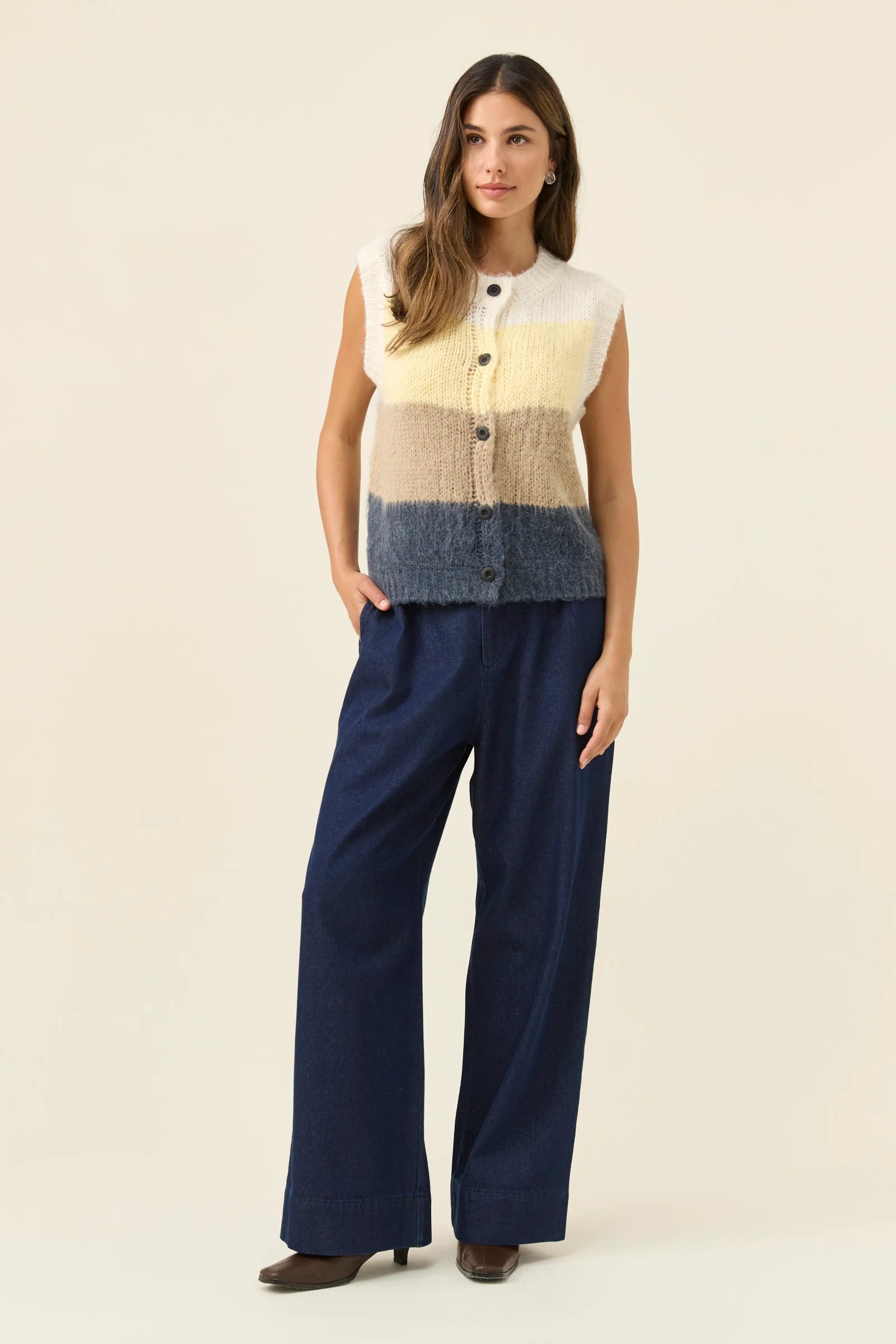 Image of Woman wearing Isle of Mine Pallas Stripe Knit Vest in butter paired with denim jeans on a plain background 
