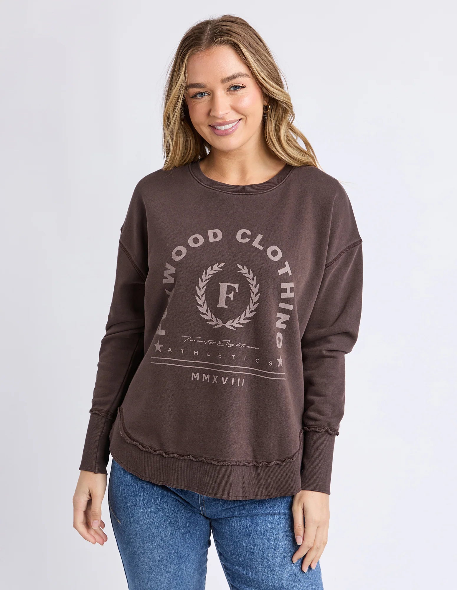 Image of Woman wearing a Foxwood Jumper in Coffee Bean with a logo and text on a white background
