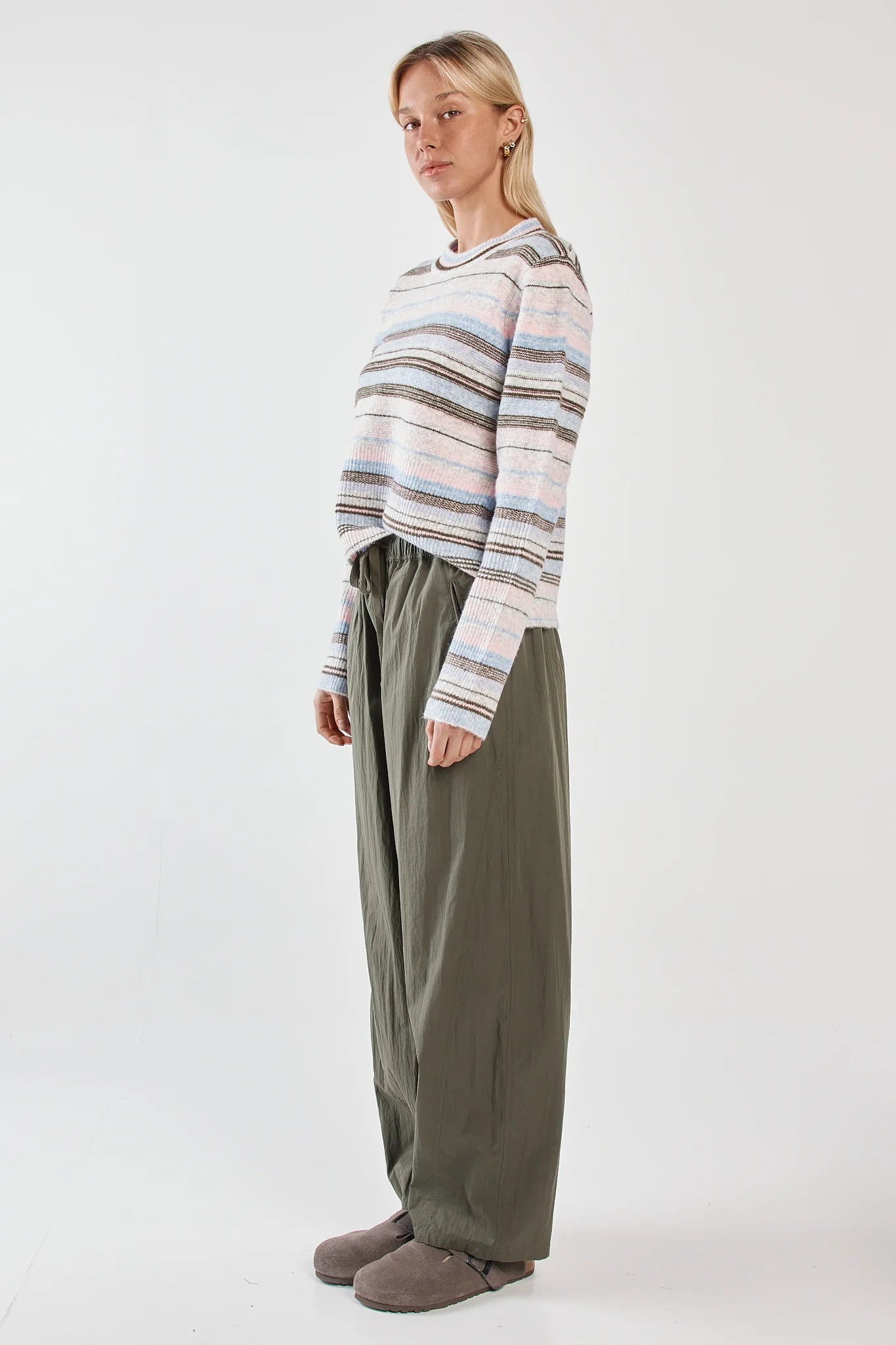 Image of Woman wearing a Sass striped sweater and green pants on a white background