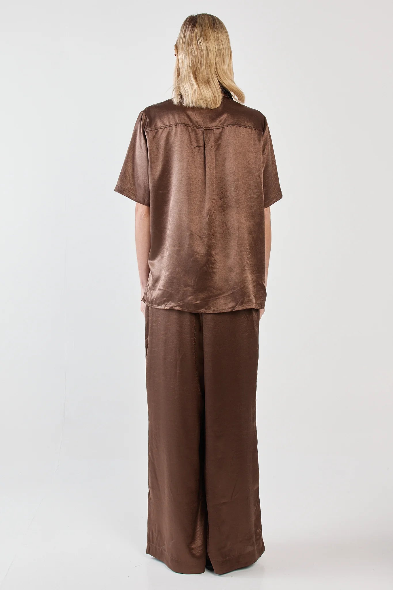 Image of Woman wearing a Sass brown outfit with wide-leg pants on a white background