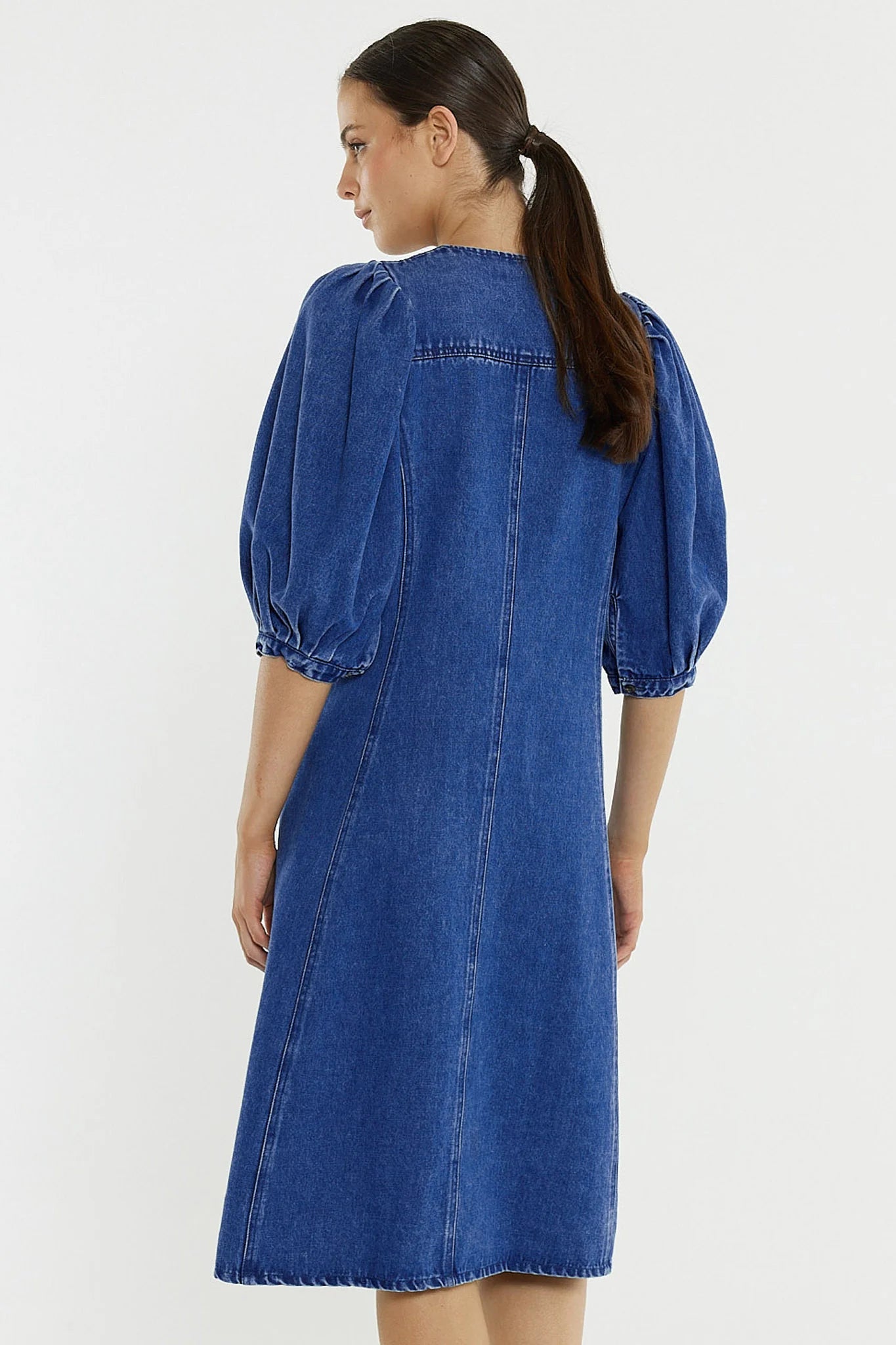 Woman wearing a Sass blue denim dress on a white background
