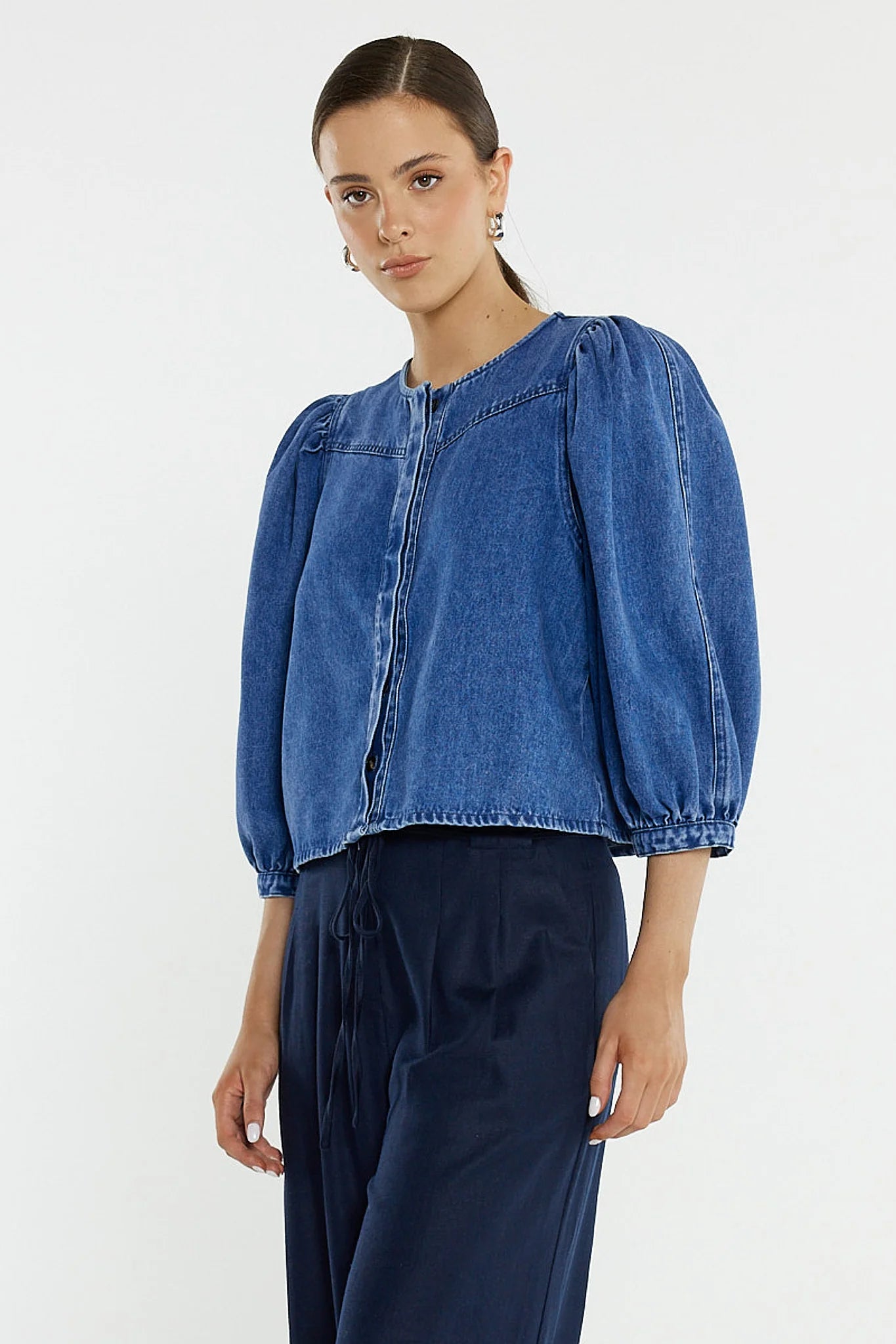 Image of Woman wearing a Sass blue denim top with balloon sleeves on a white background