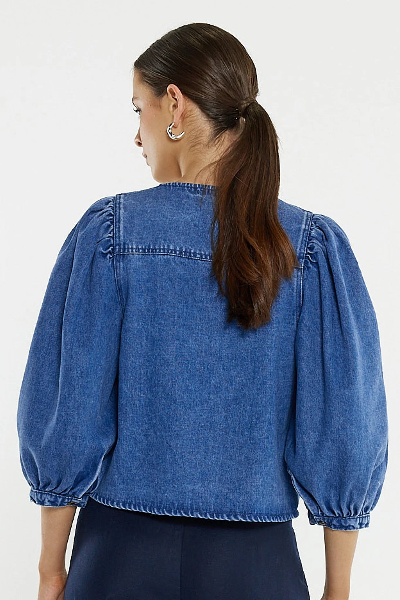 Image of Woman wearing a Sass blue denim blouse with puffed sleeves on a white background