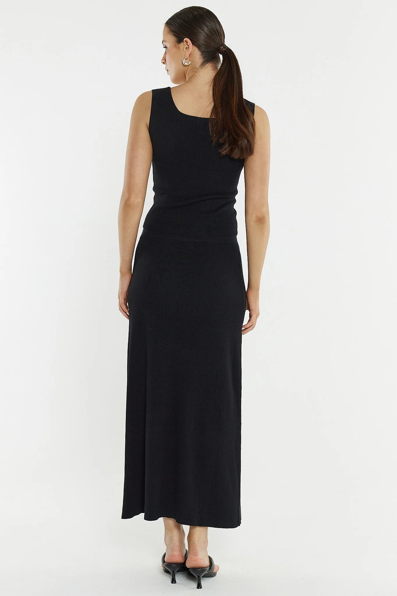 Woman wearing a Sass black knit skirt on a white background