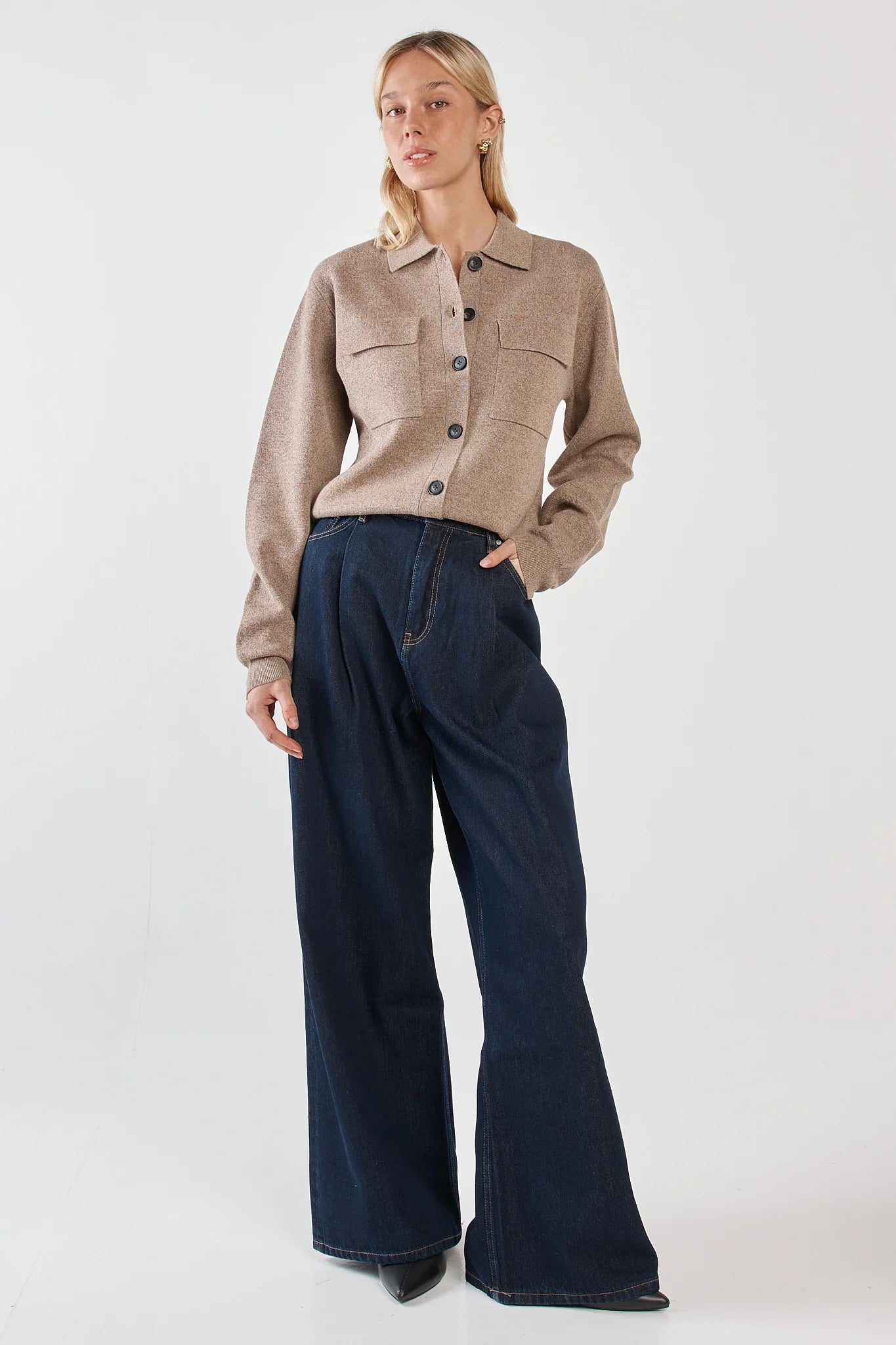 Image of Woman wearing a Sass beige jacket and dark blue jeans on a white background