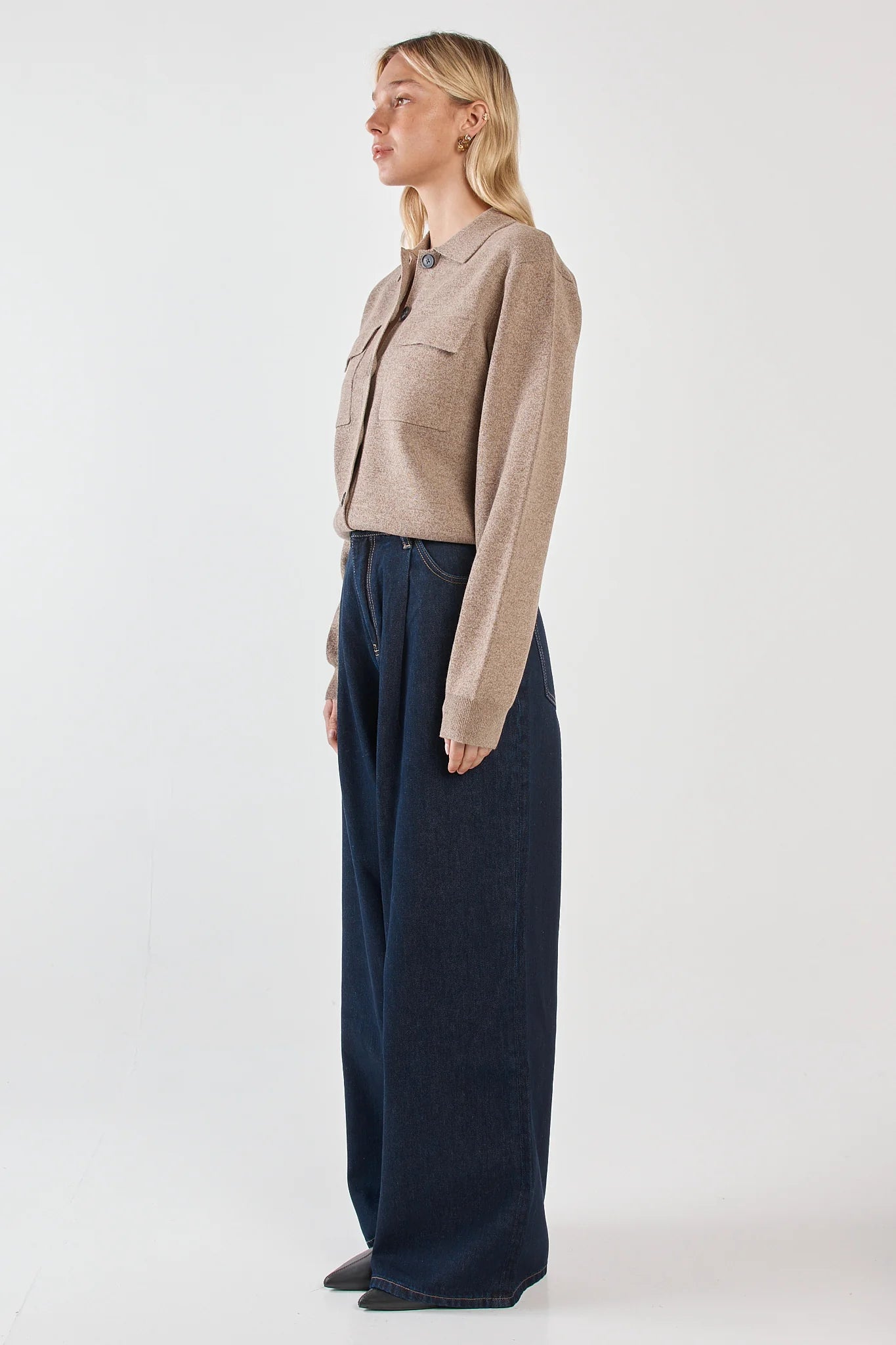 Image of Woman wearing a Sass beige jacket and dark blue pants on a white background