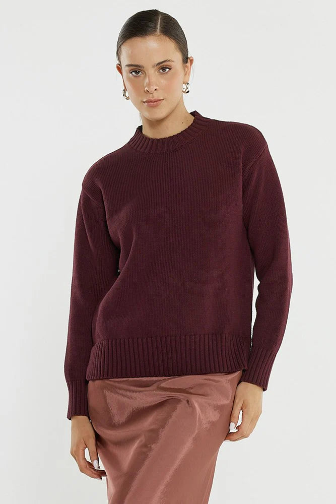 Image of Woman wearing a Sass burgundy sweater and pink pants on a white background