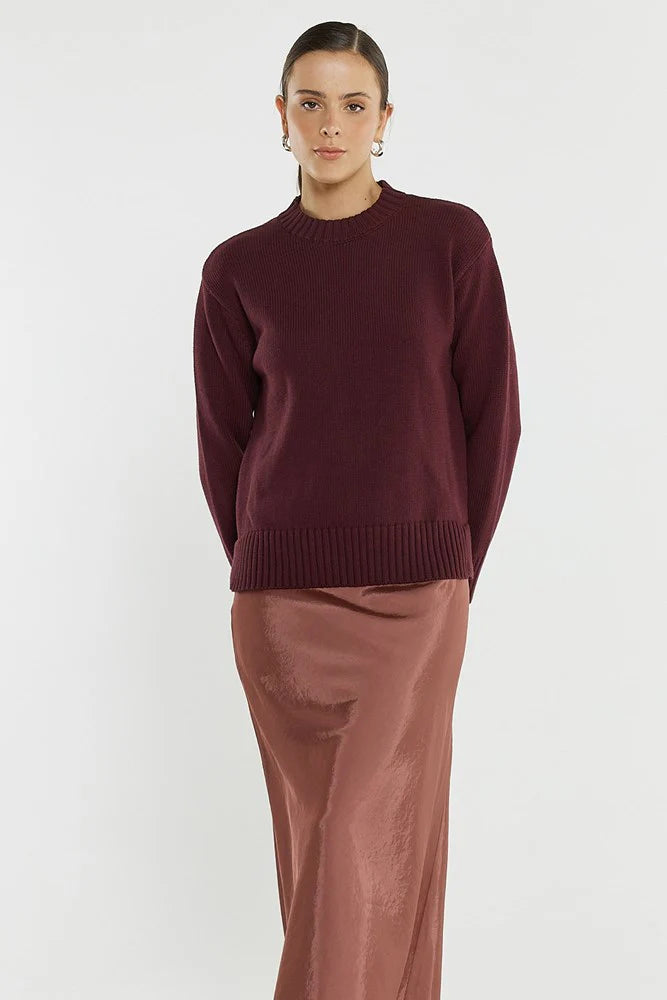 Woman wearing a Sass burgundy sweater and brown pants on a white background