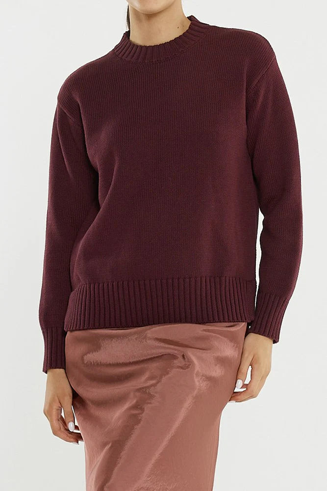 Image of Woman wearing a Sass maroon sweater and pink pants on a white background