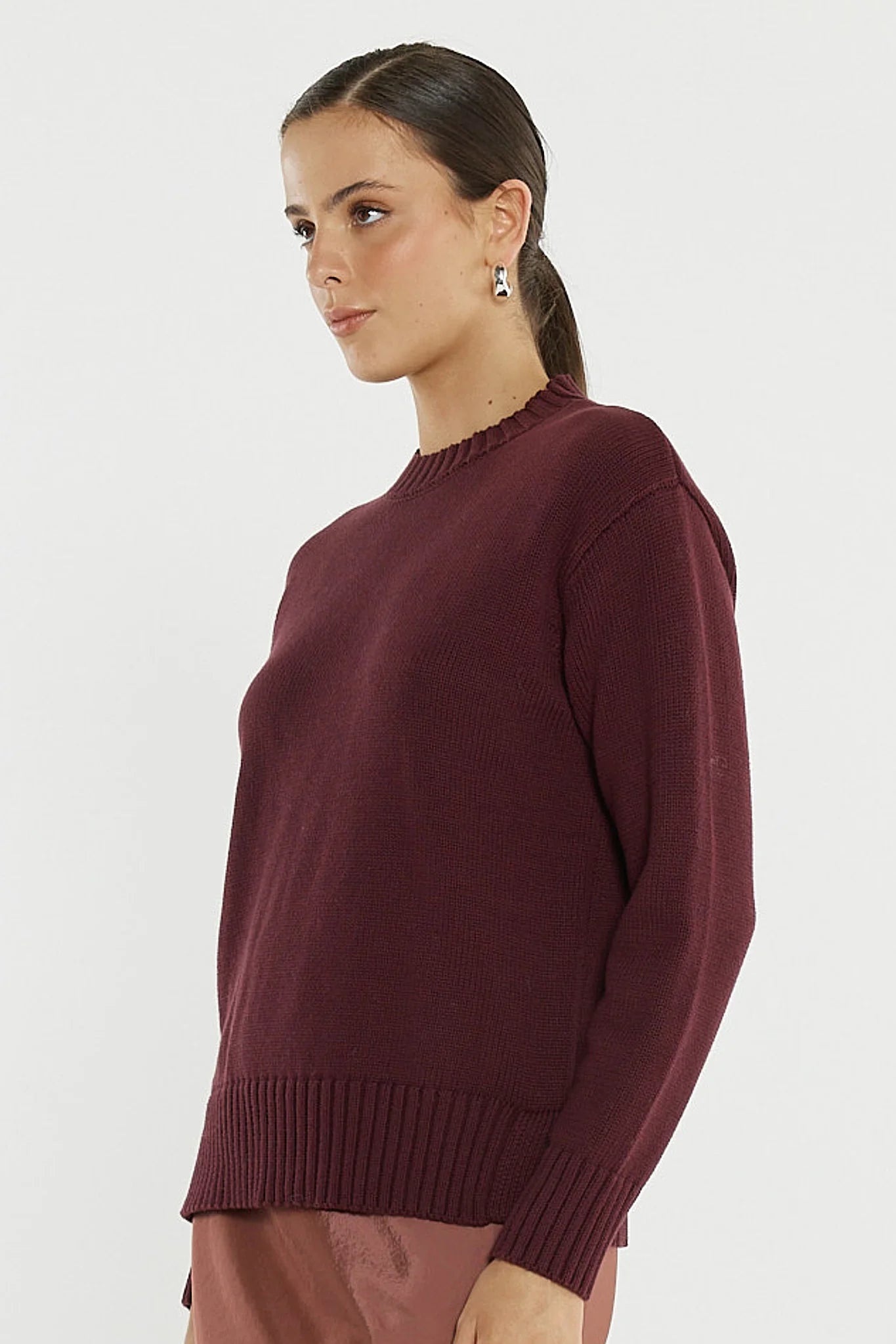 Image of Woman wearing a Sass burgundy sweater against a white background