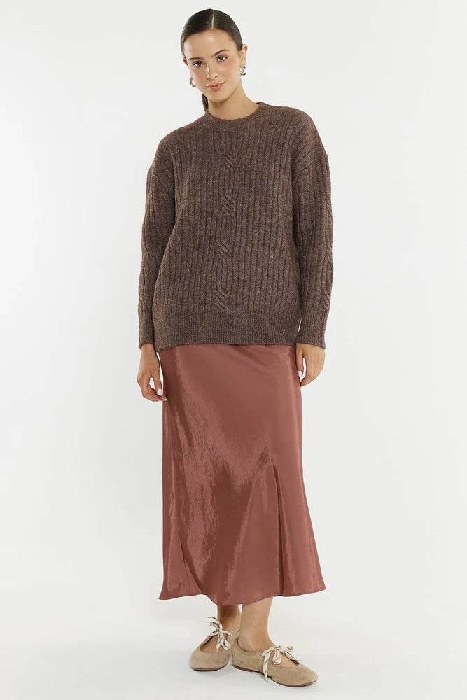 Woman wearing a Sass brown sweater and rust-colored skirt on a white background