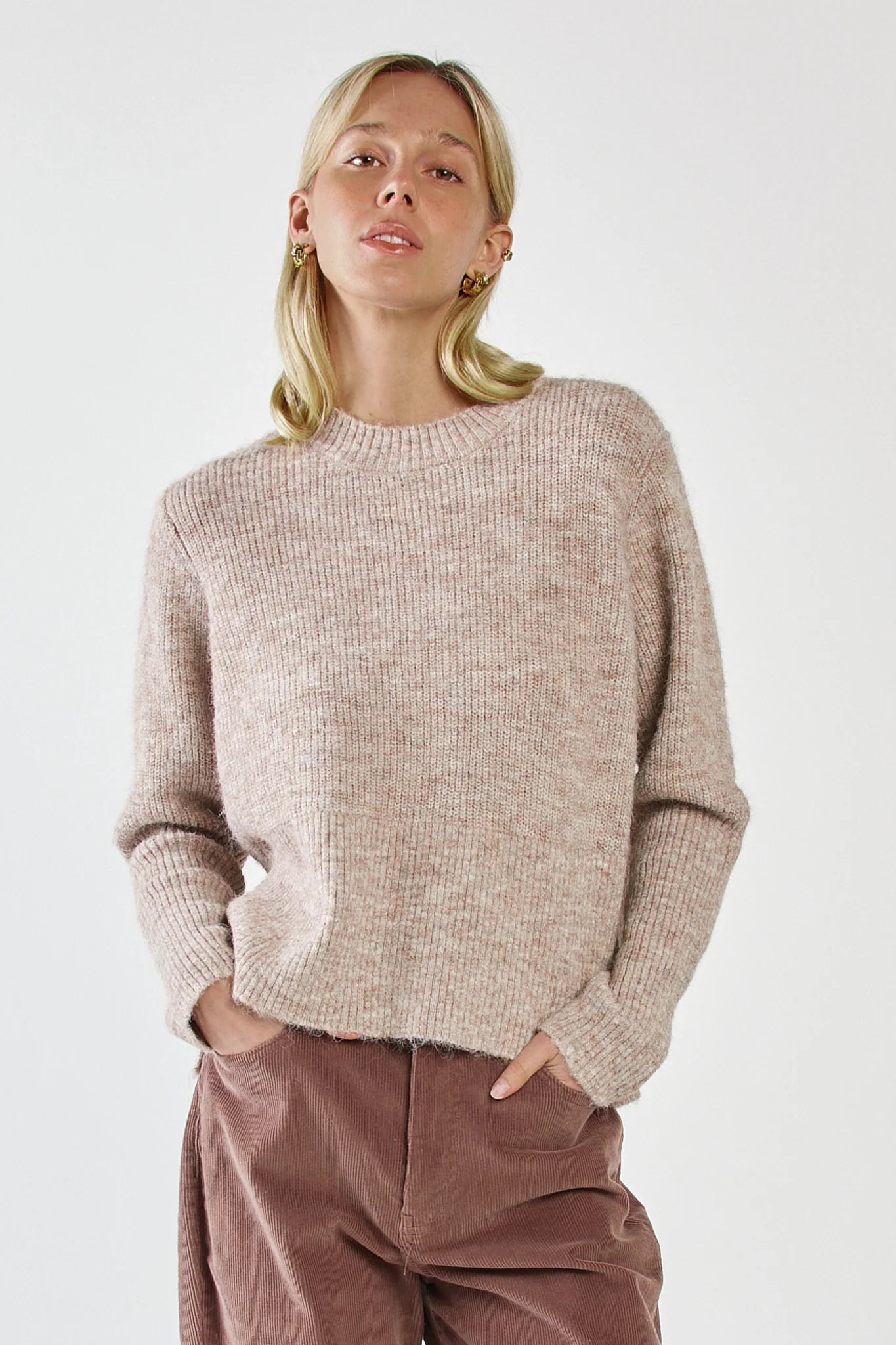 Image of Woman wearing a Sass beige sweater and brown pants against a white background
