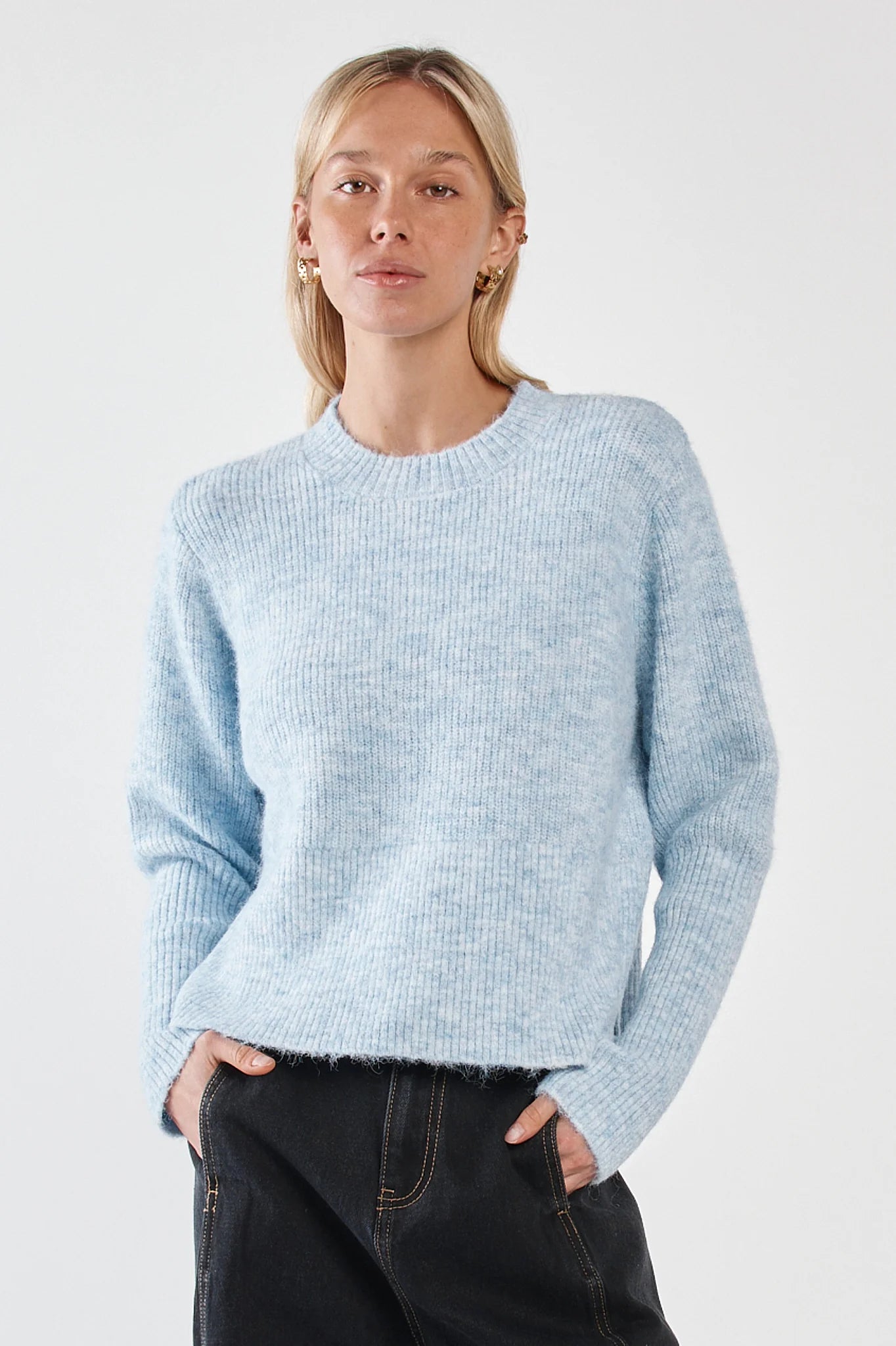Woman wearing a Sass light blue sweater against a white background