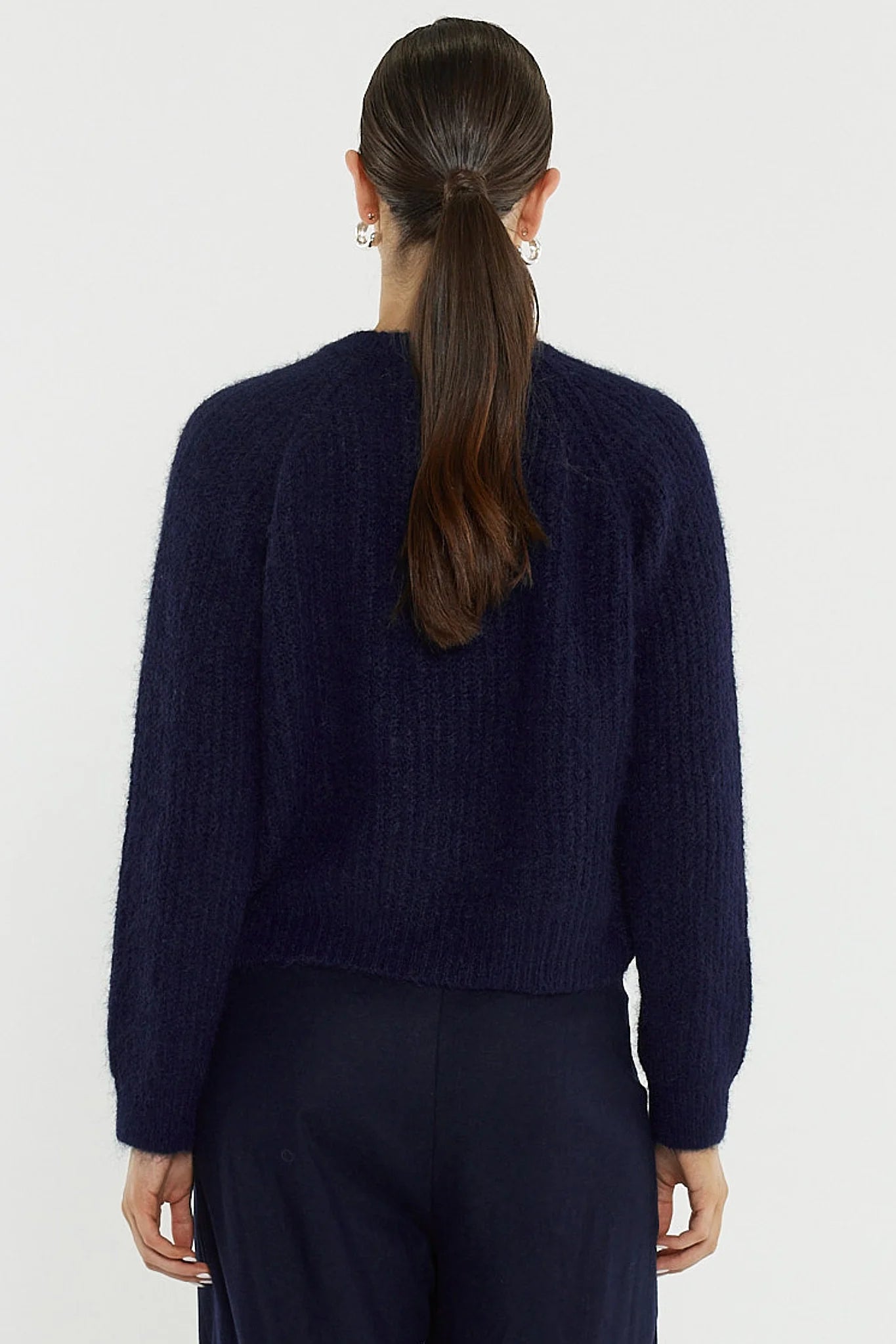 Image of Woman wearing a Sass dark blue sweater against a white background