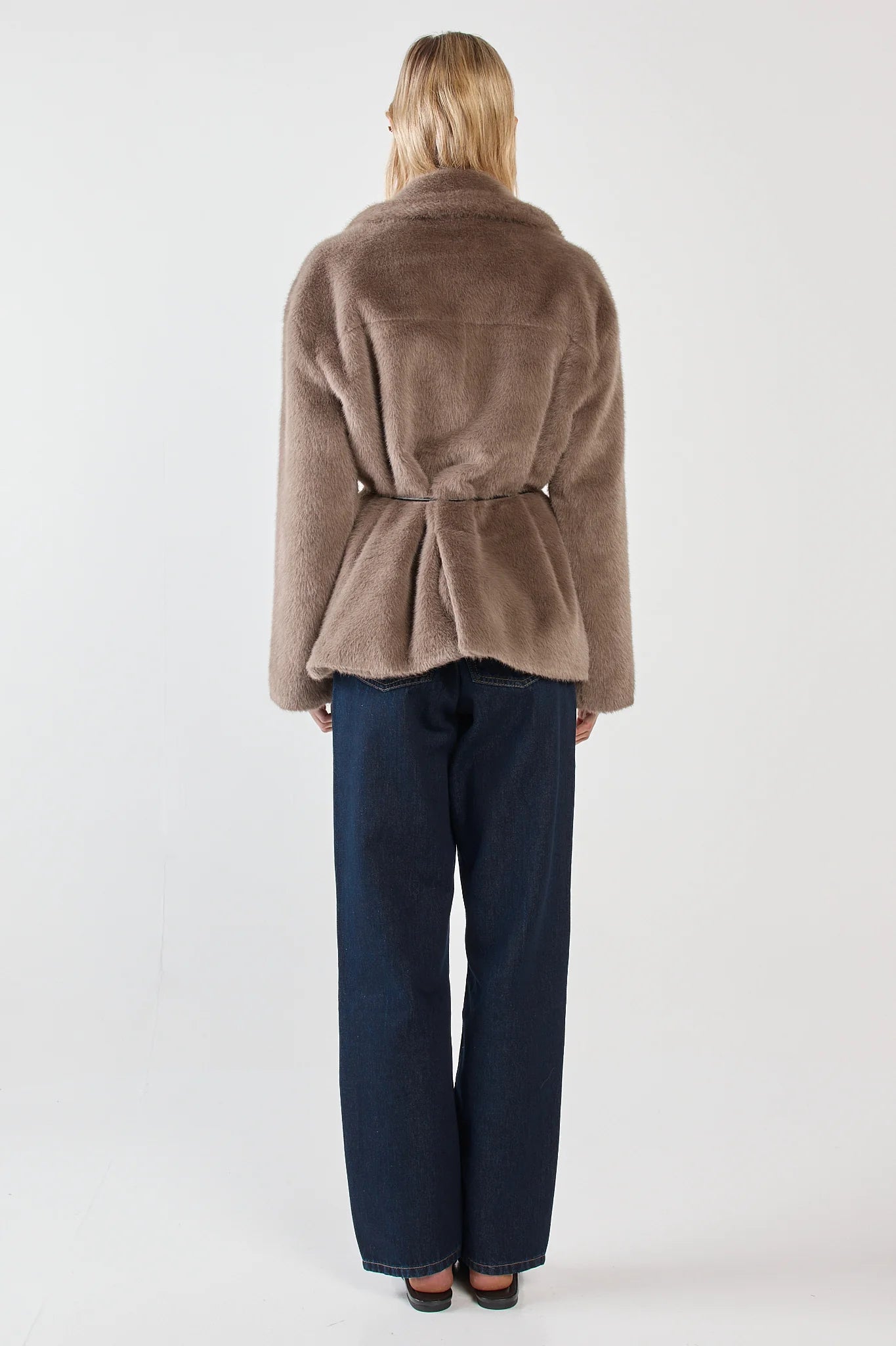 Image of Woman wearing a sass brown coat and blue jeans on a white background