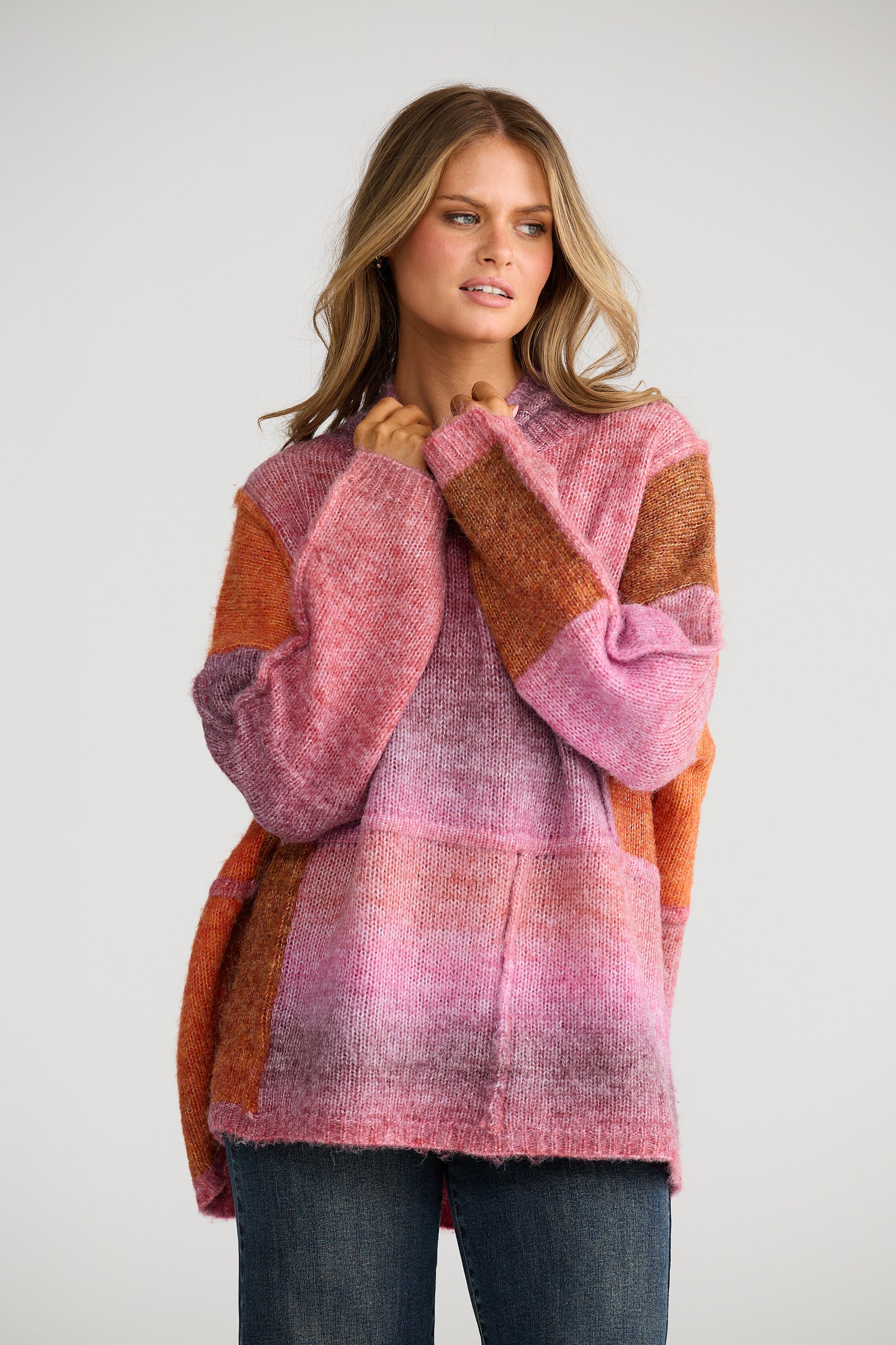 Woman wearing a Talisman pink and orange patterned sweater against a white background