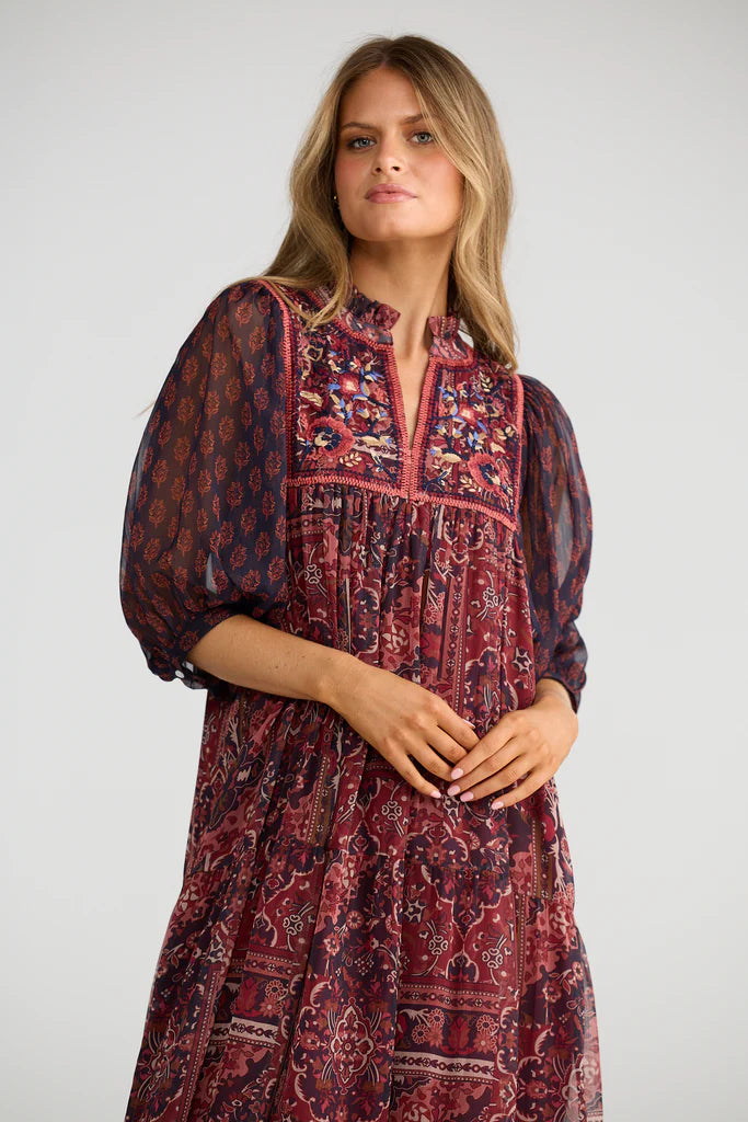 Woman wearing a Talisman patterned dress against a plain background