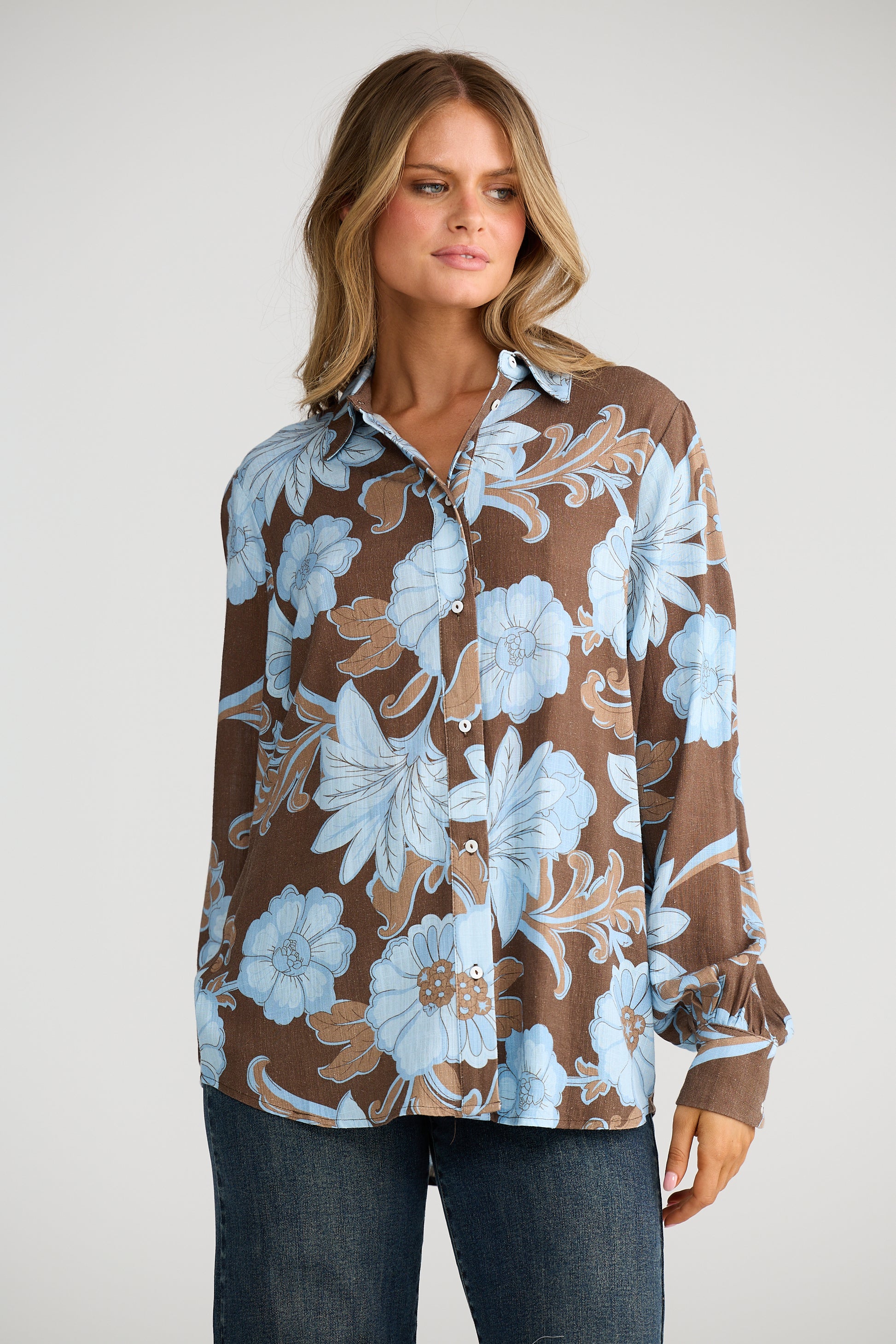 Woman wearing a Talisman brown floral blouse with blue flowers on a white background