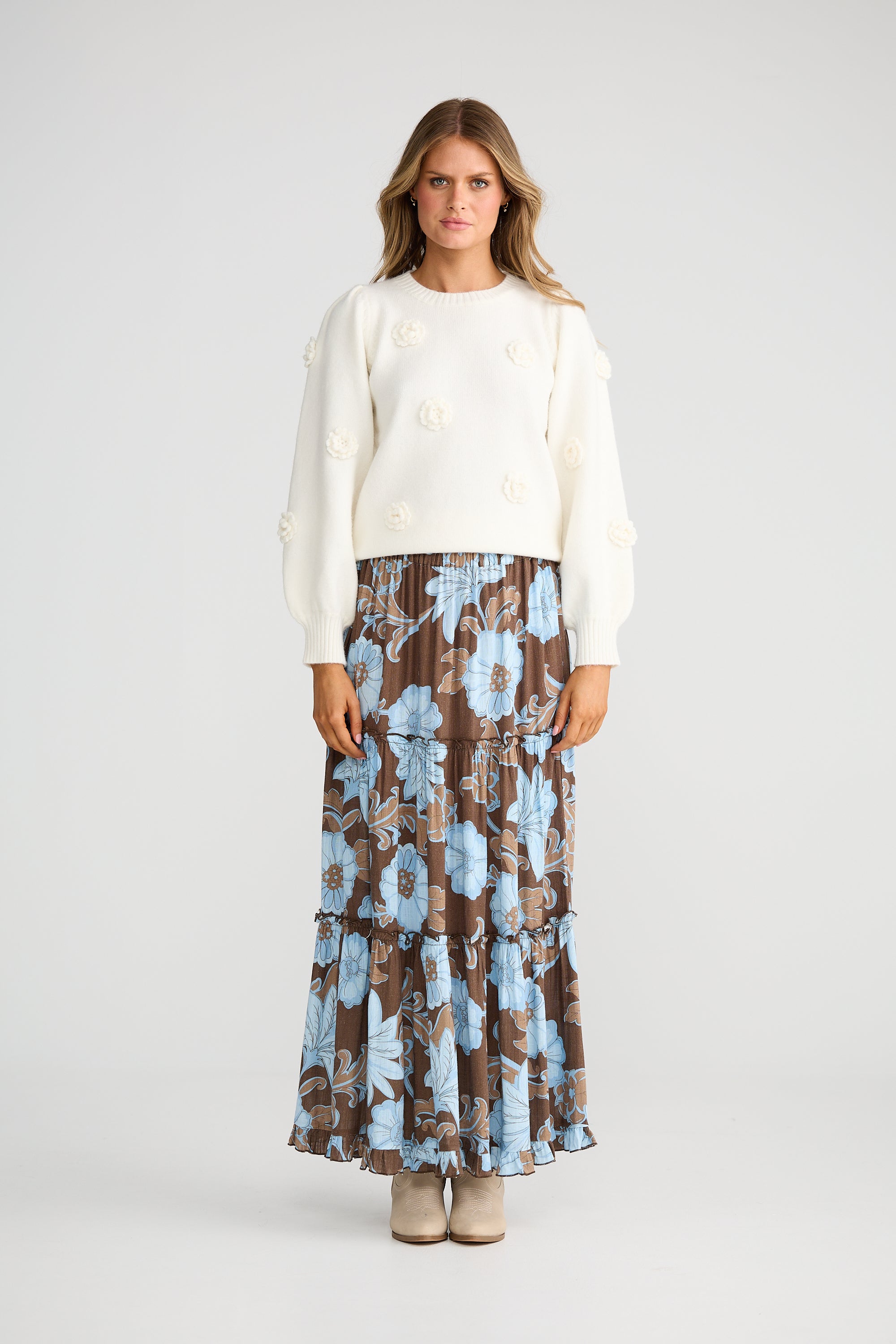 Collection of Woman wearing a Talisman white sweater and Talisman floral skirt on a white background in a gallery layout