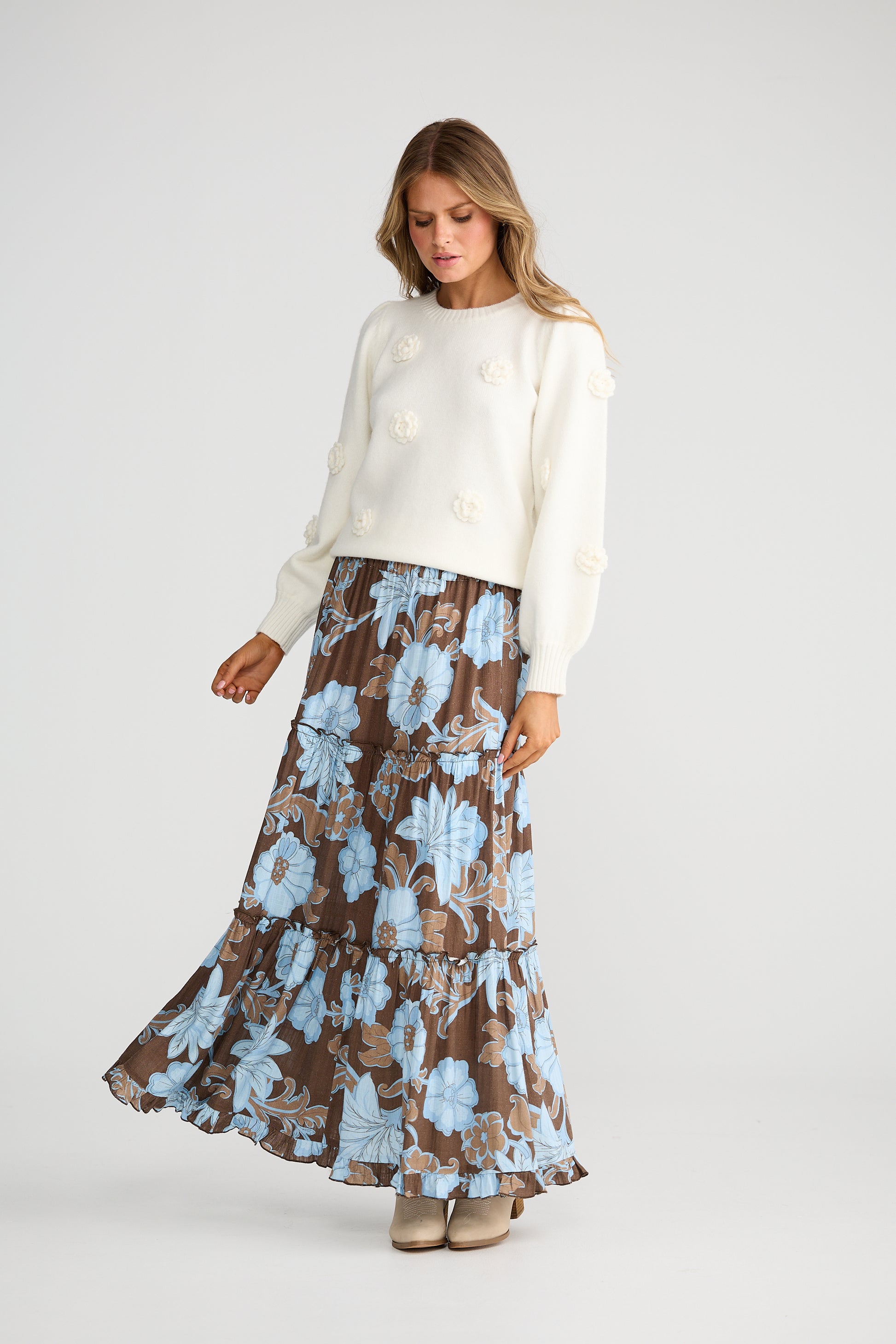 Woman wearing a Talisman white sweater and Talisman floral skirt on a white background