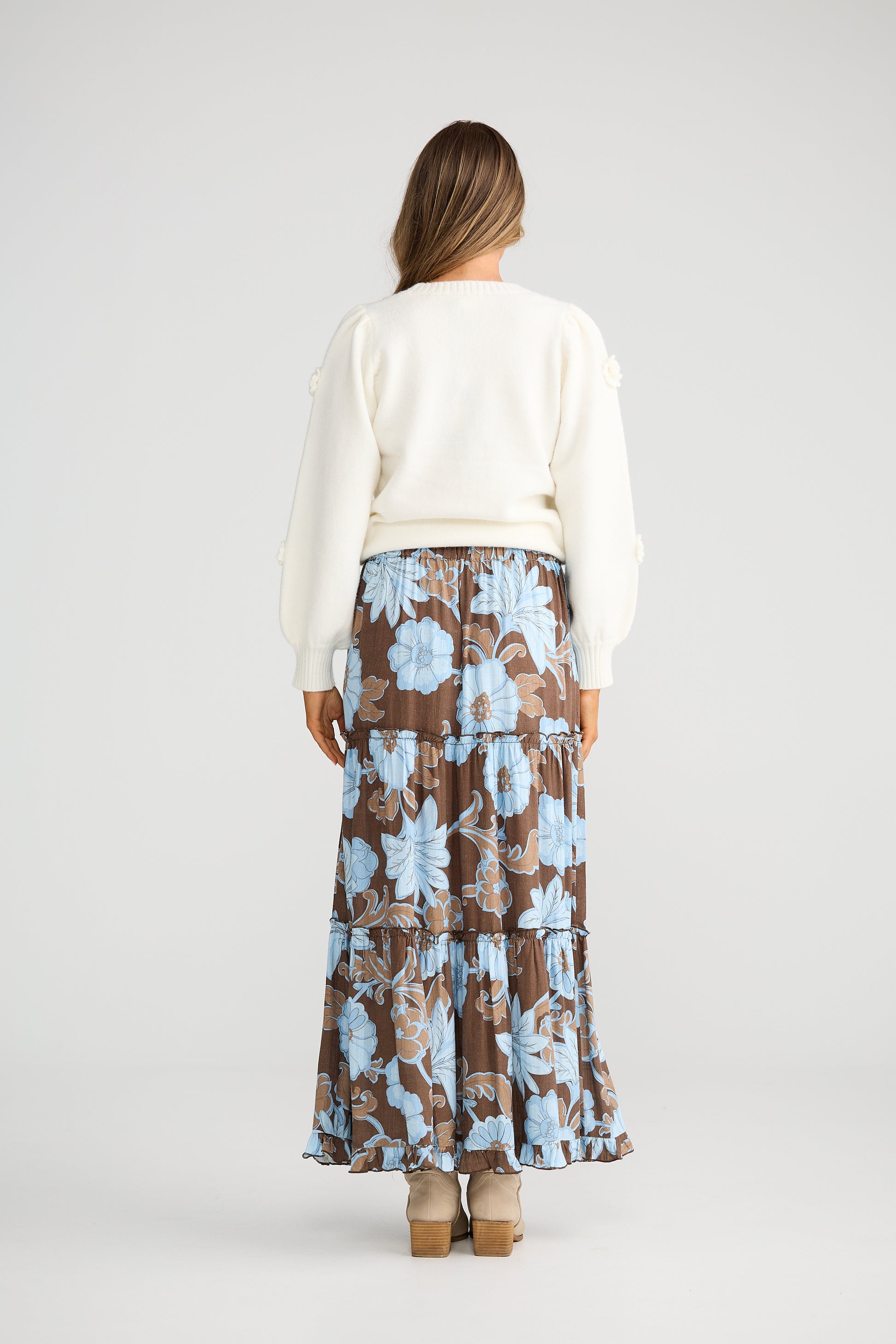 Woman wearing a white top and Talisman floral skirt on a plain background