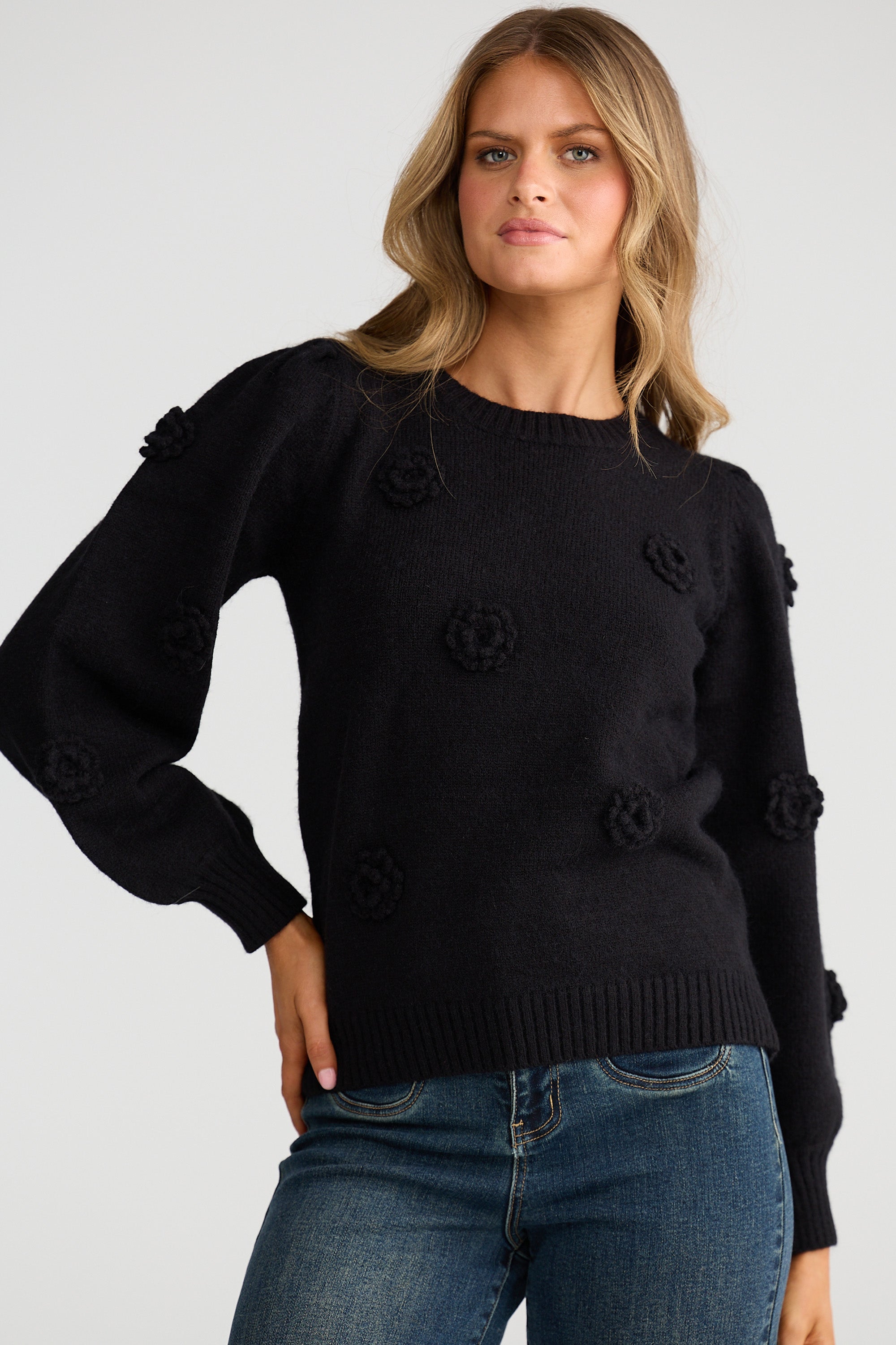 Collection of Woman wearing a Talisman black sweater with floral details on a plain background in a gallery layout