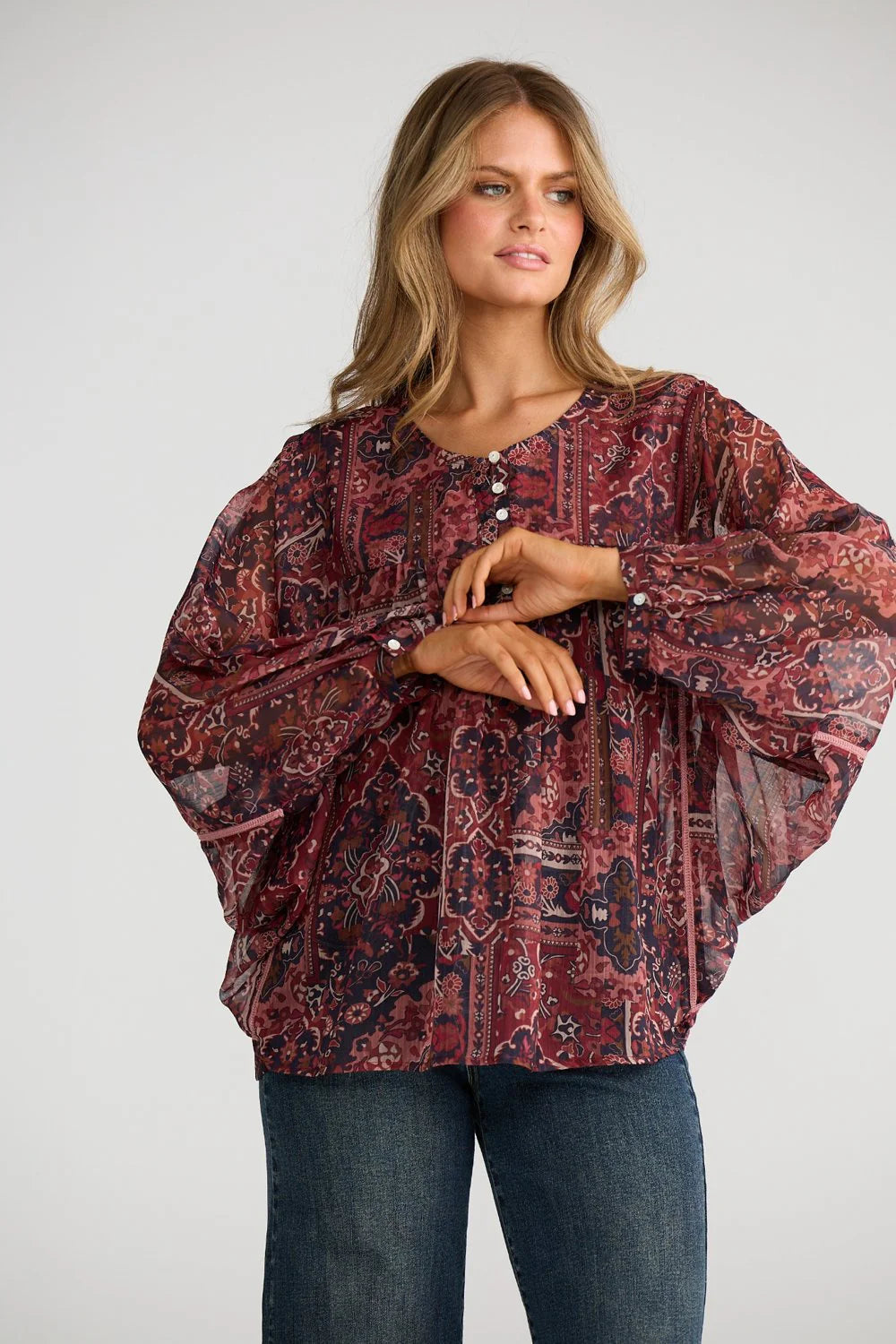 Image of Woman wearing a Talisman patterned blouse and jeans on a plain background