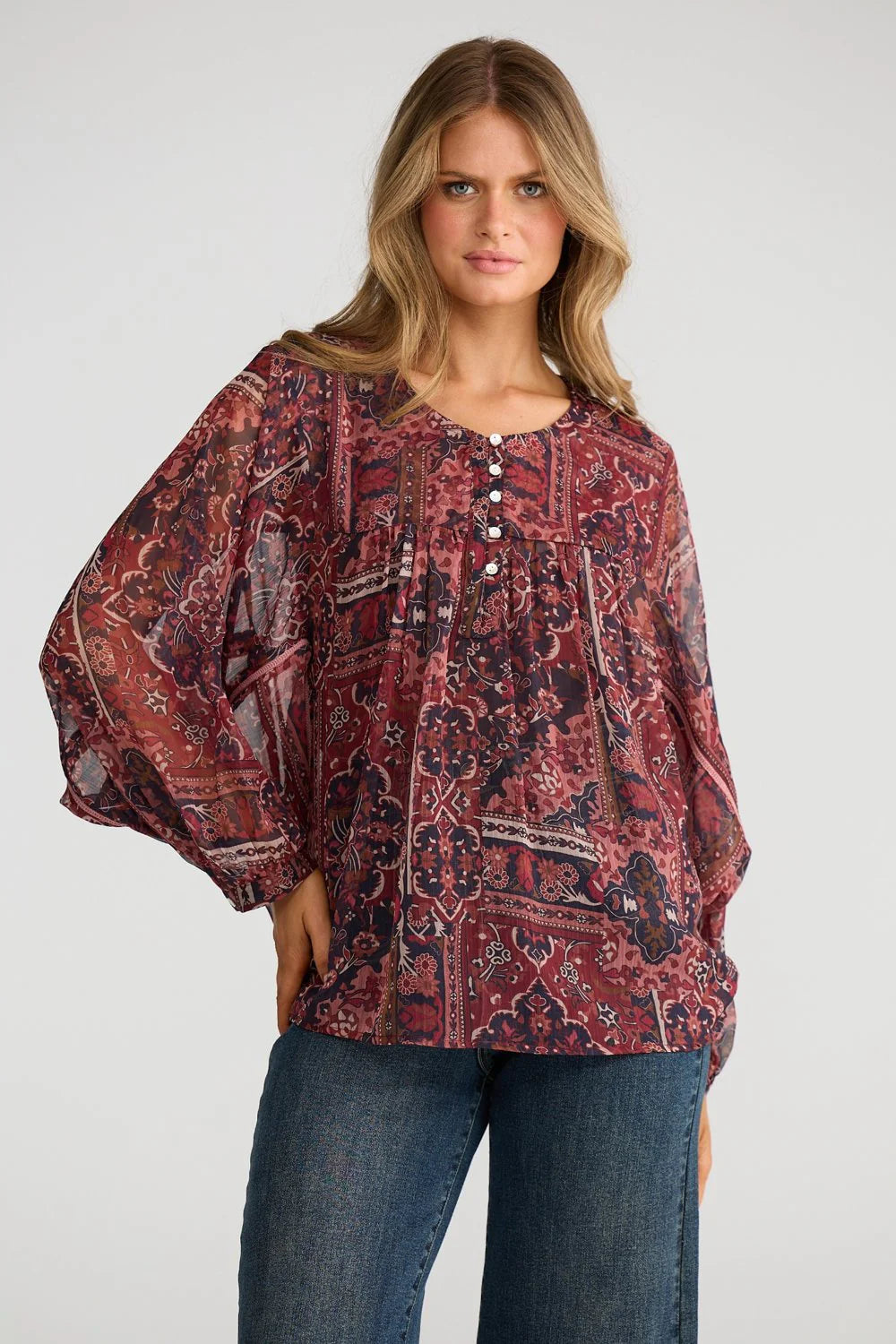 Image of Woman wearing a Talisman patterned blouse and jeans on a white background