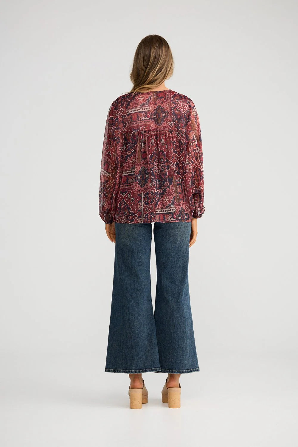 Image of Woman wearing a Talisman patterned blouse and blue jeans on a white background