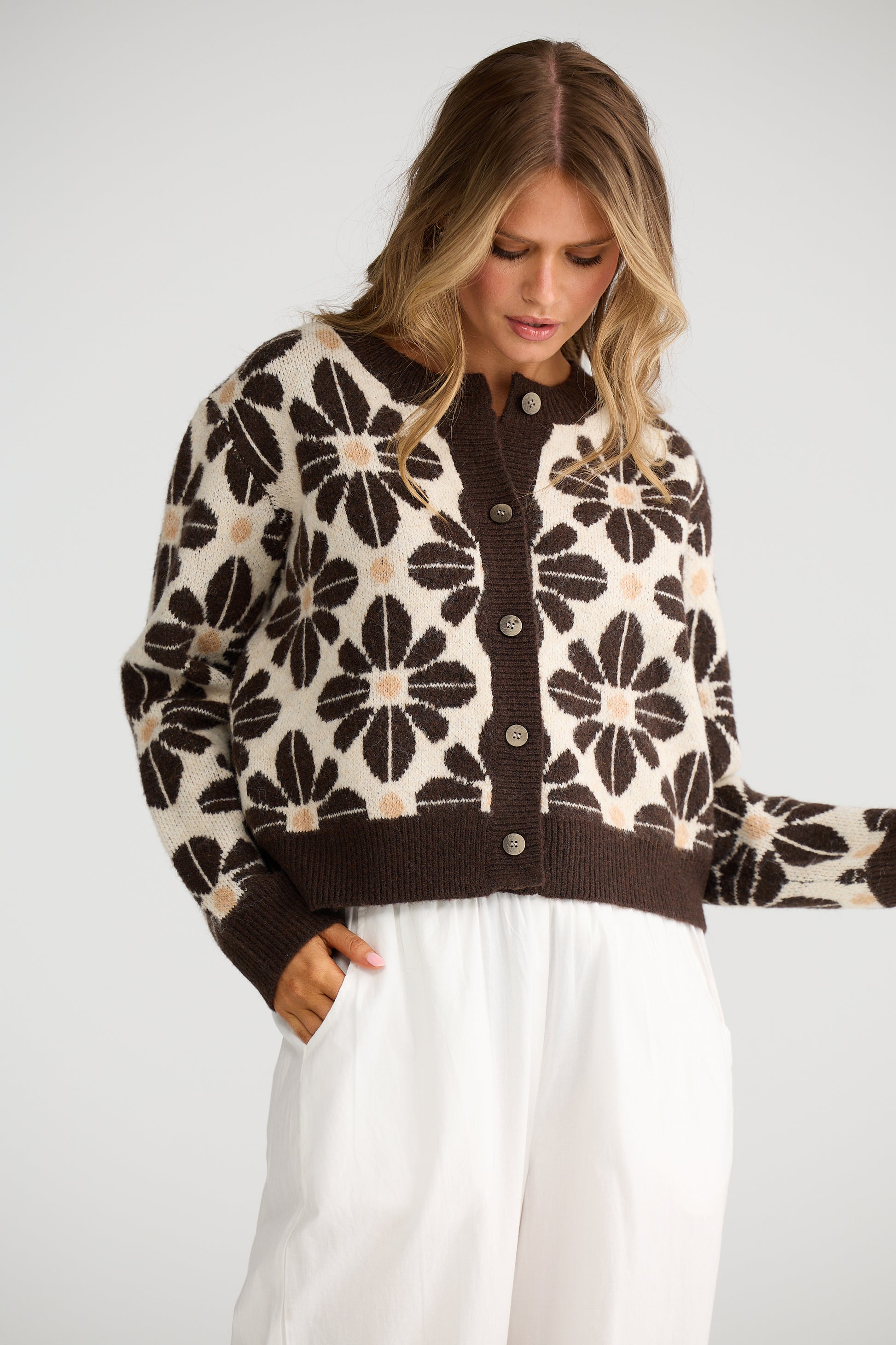 Woman wearing Talisman cardi with white pants on a beige background 