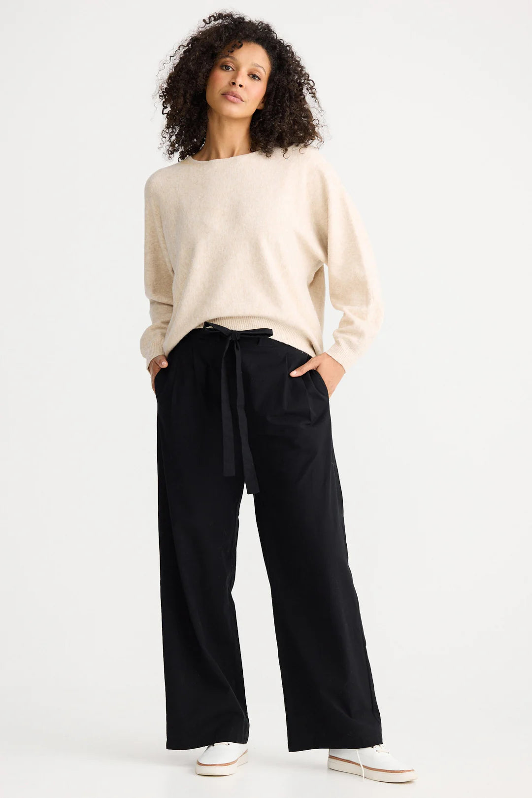 Image of Woman wearing a beige sweater and The Shanty Corporation black wide-leg pants on a white background