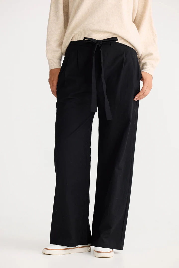Woman wearing The Shanty Corporation black wide-leg pants with a beige sweater on a white backgrounD
