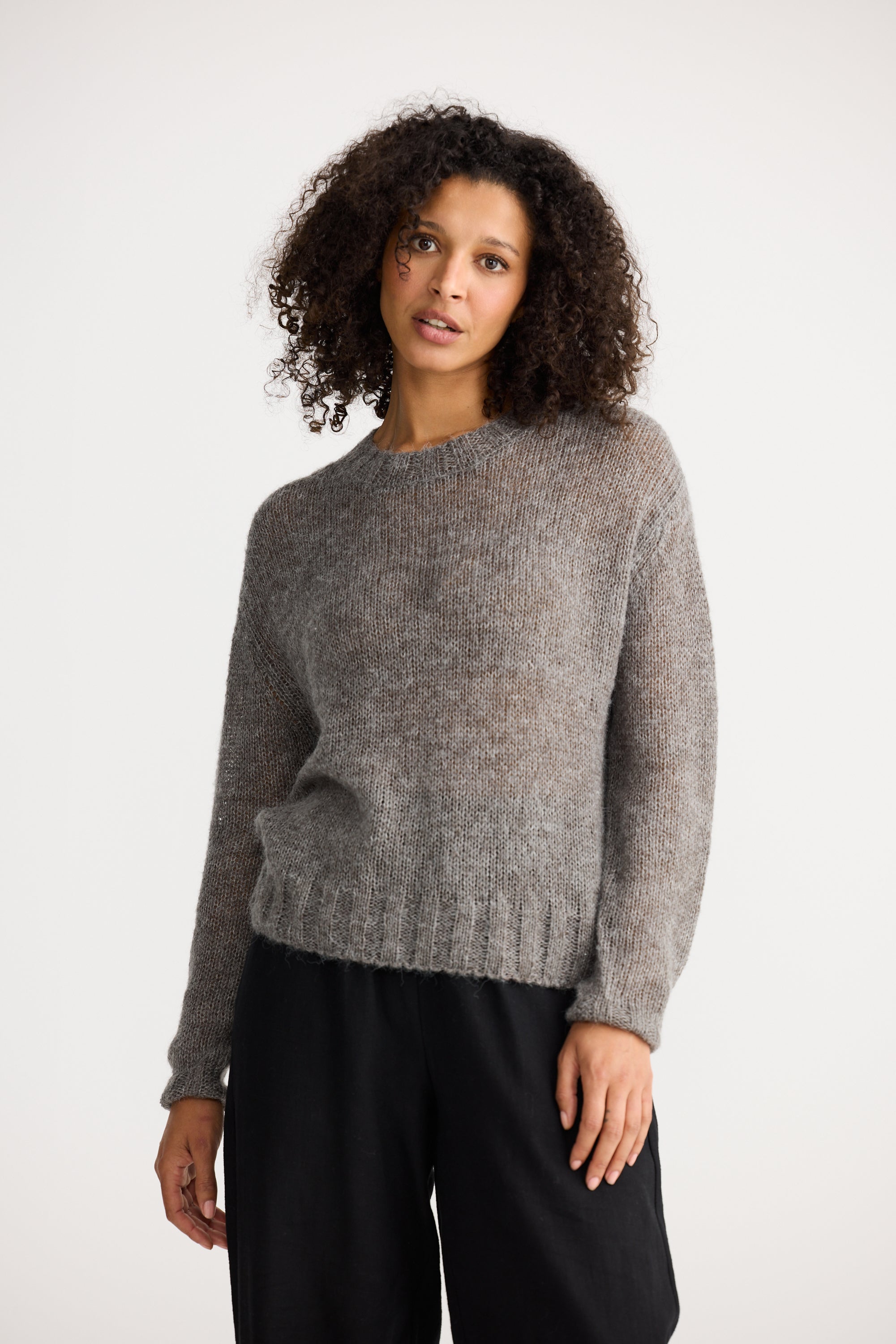 Image of Woman wearing a Shanty Corporation grey sweater and black pants on a white background