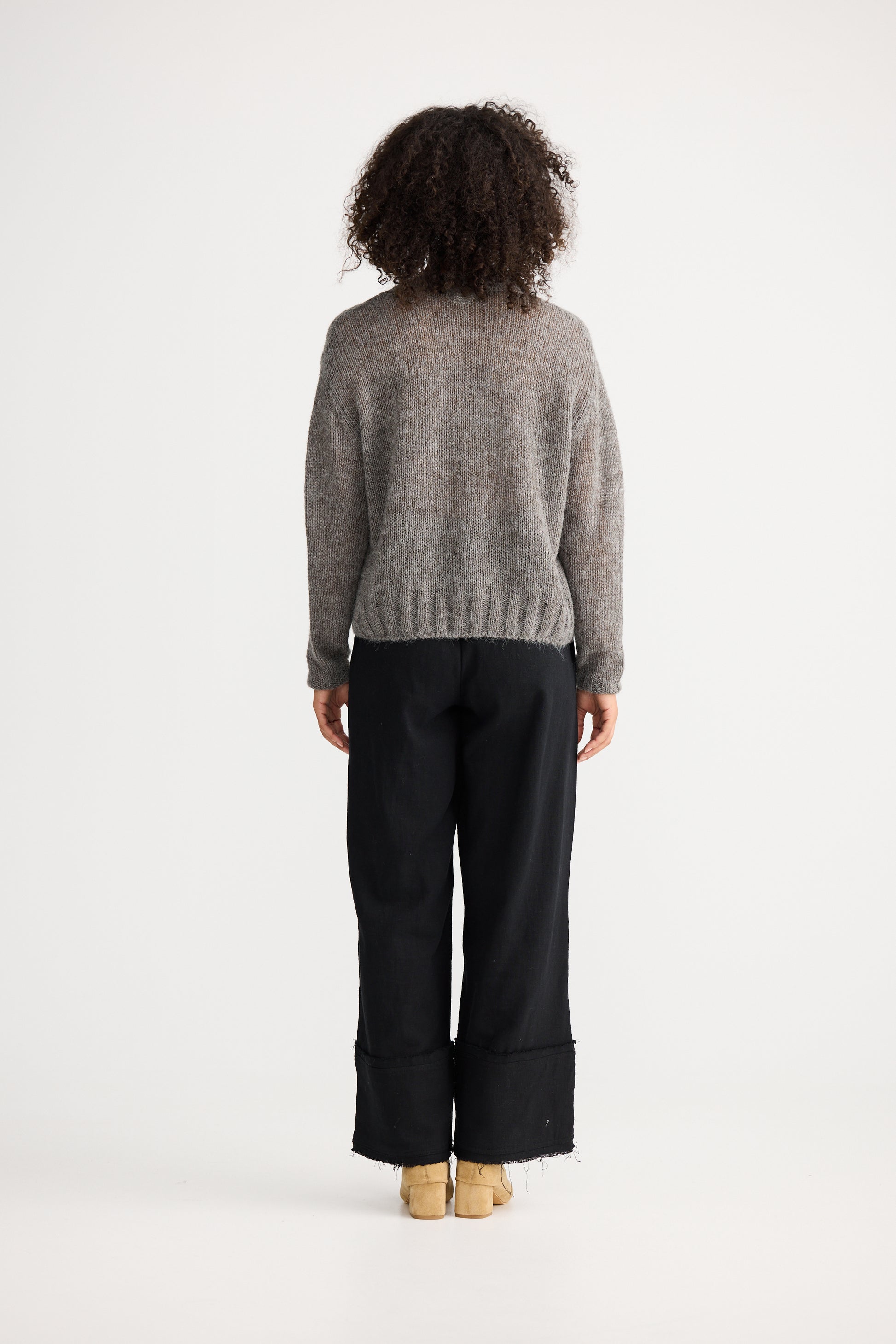 Person wearing a Shanty Corporation grey sweater and black pants on a white background