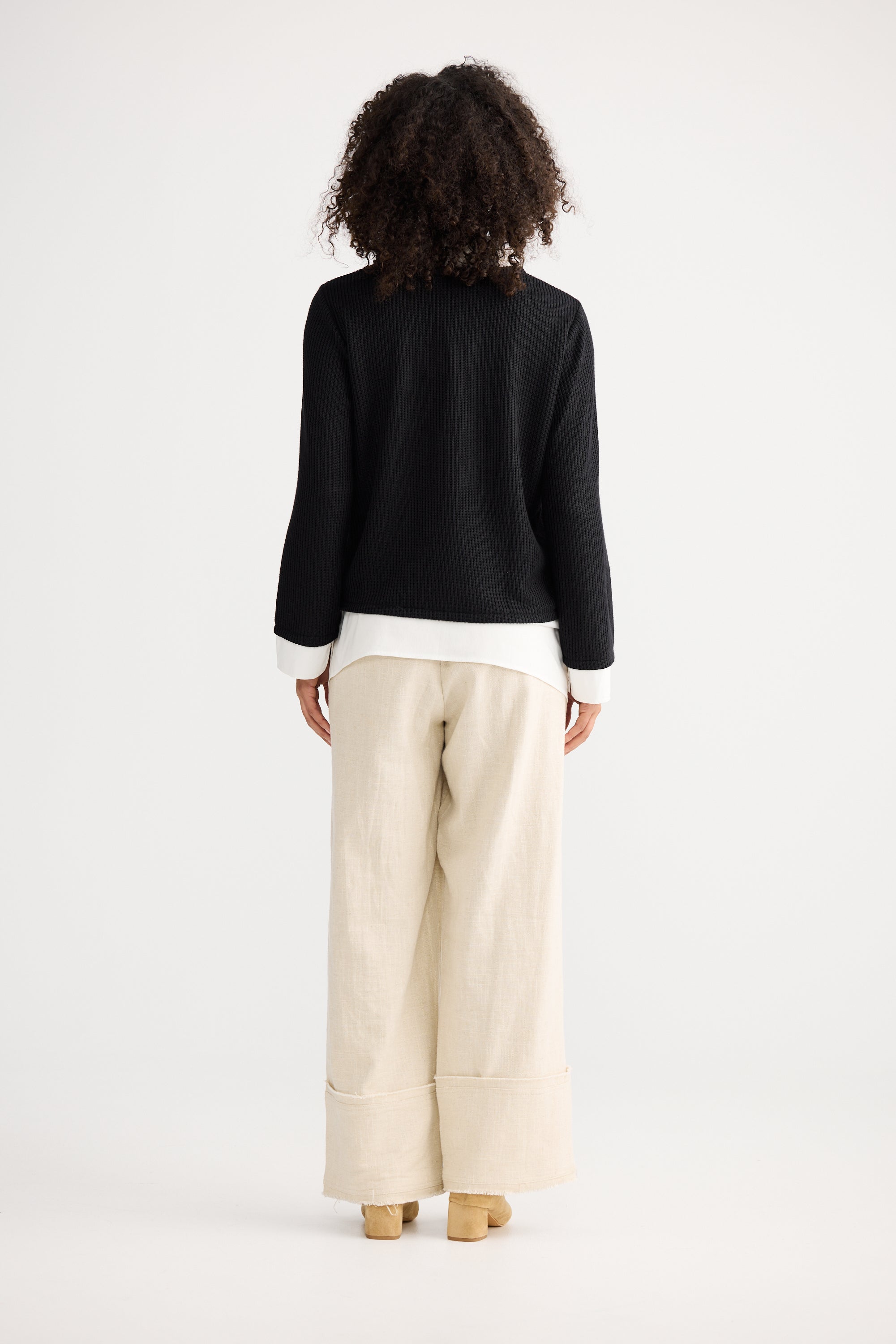 Image of Woman wearing a Shanty Corporation black top and beige pants on a white background