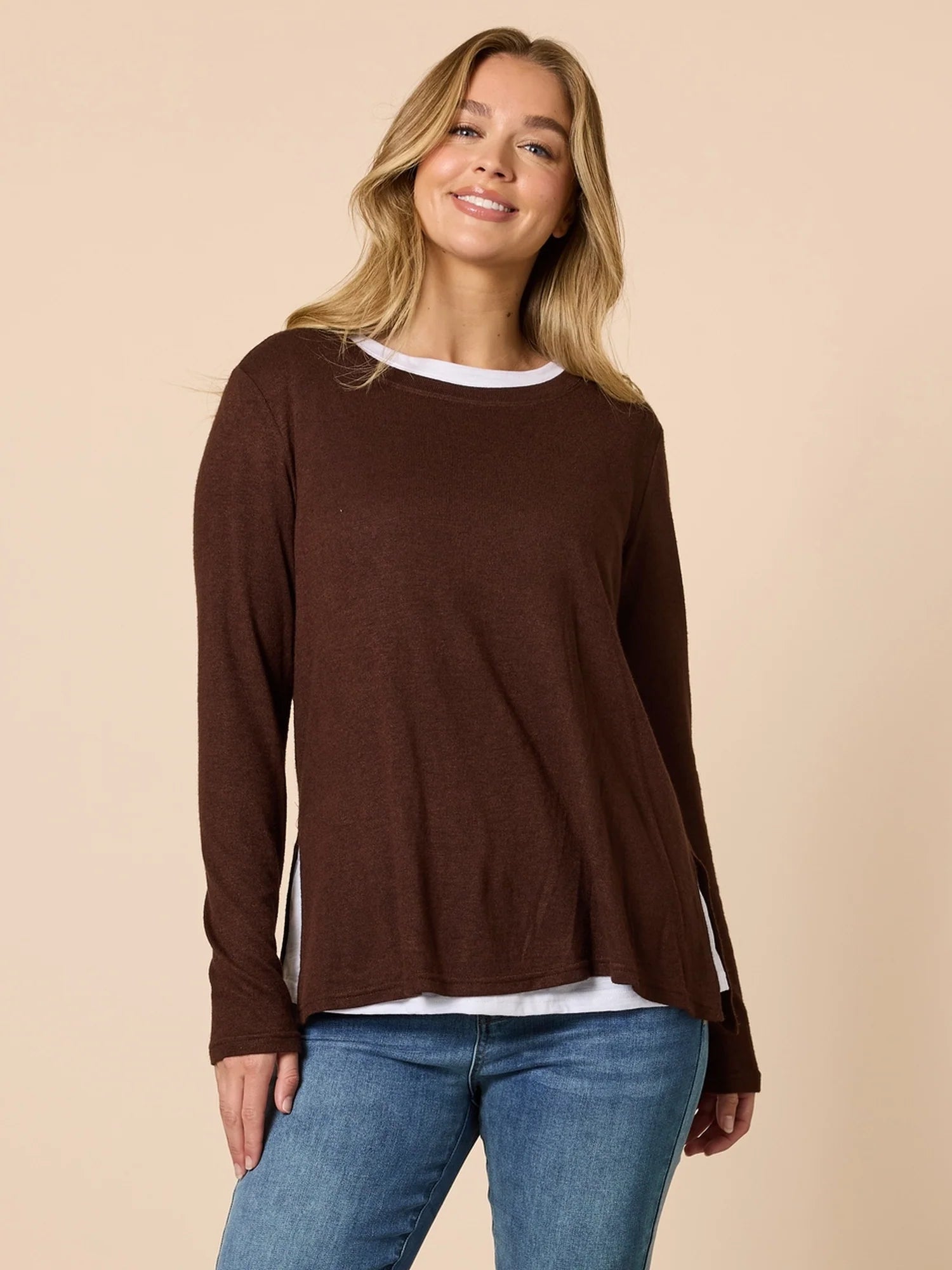 Woman wearing a Threadz brown long-sleeve top and blue jeans on a beige background