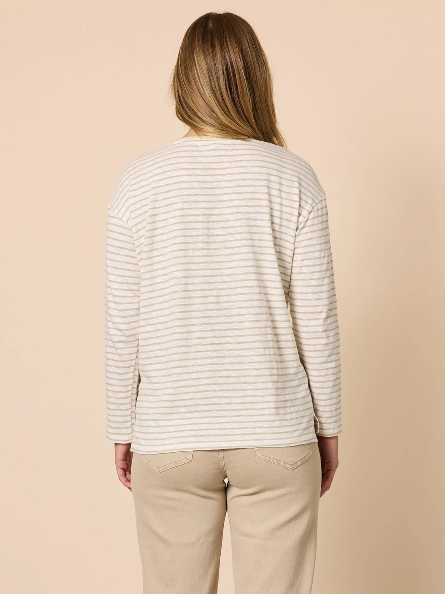 Collection of Woman wearing a Threadz striped long-sleeve shirt and beige pants on a beige background in a gallery layout